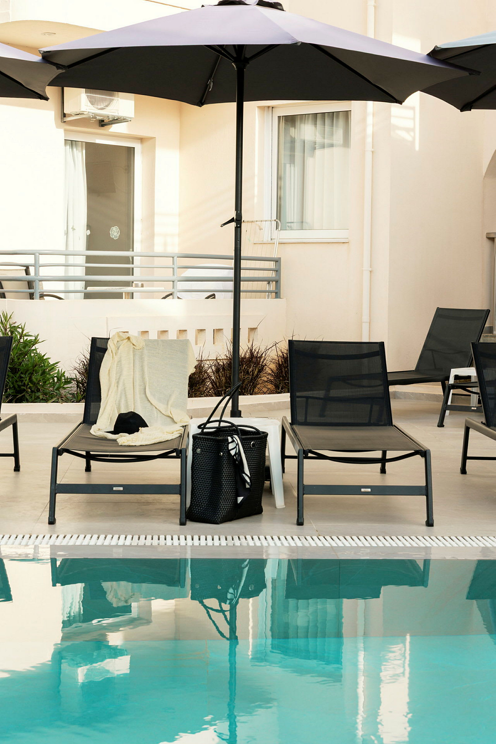 Solstolar med parasoll vid en pool. (AI-genererad text)