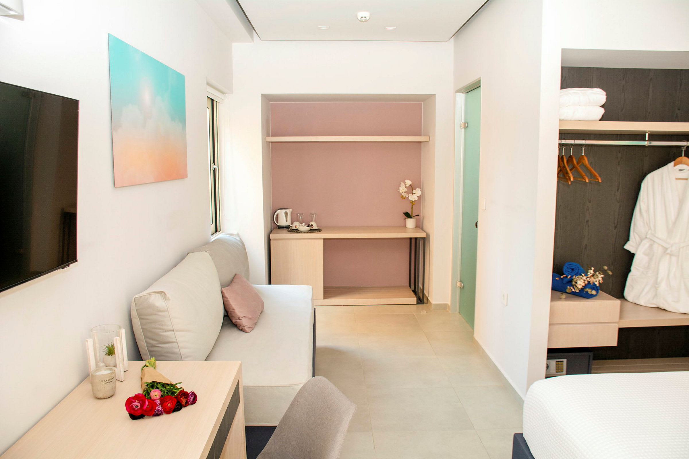 Ett modernt hotellrum med soffa, bord, och garderob. (AI-genererad text)