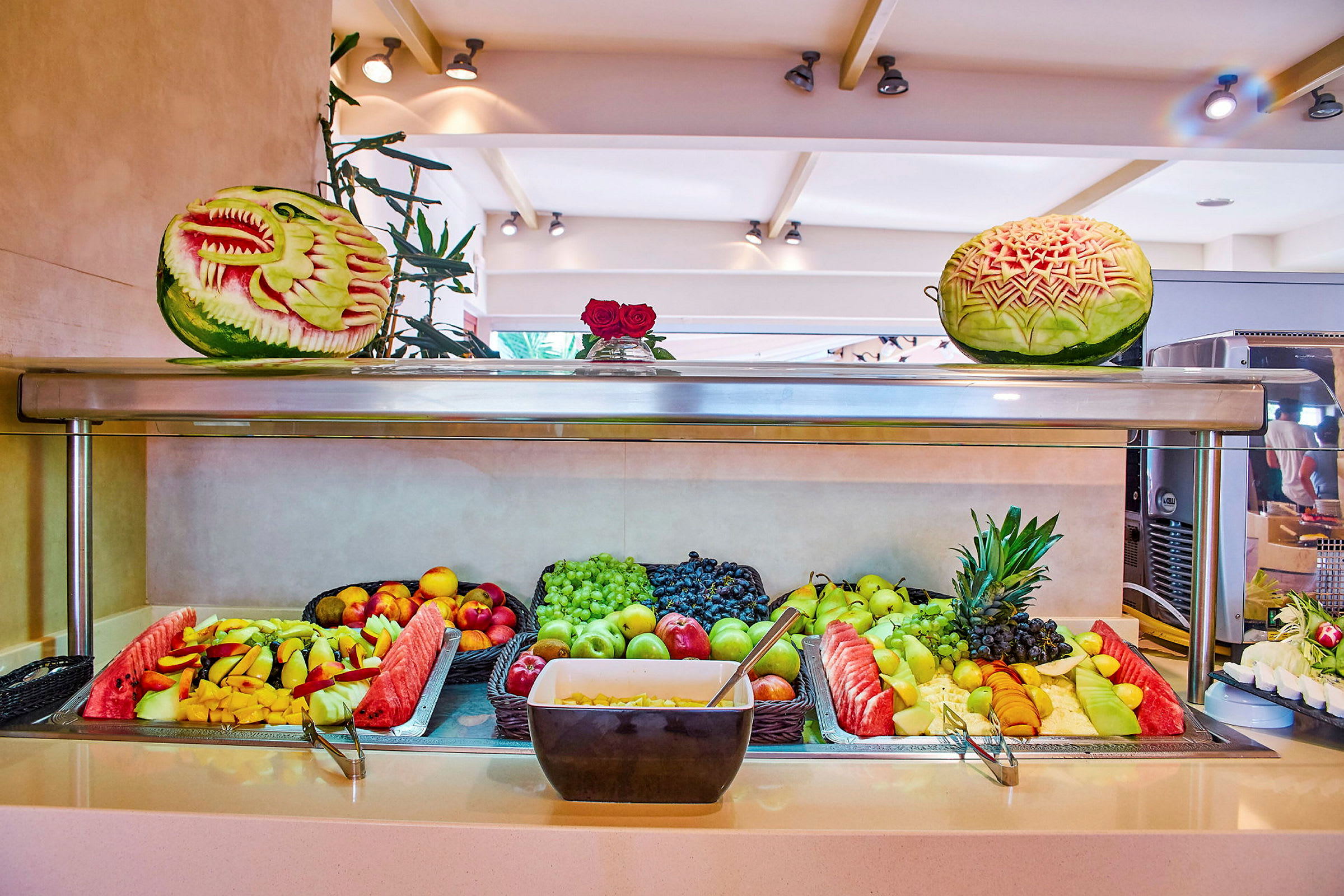 En buffé med färsk frukt, inklusive vattenmelon och druvor, samt dekorerade meloner. (AI-genererad text)