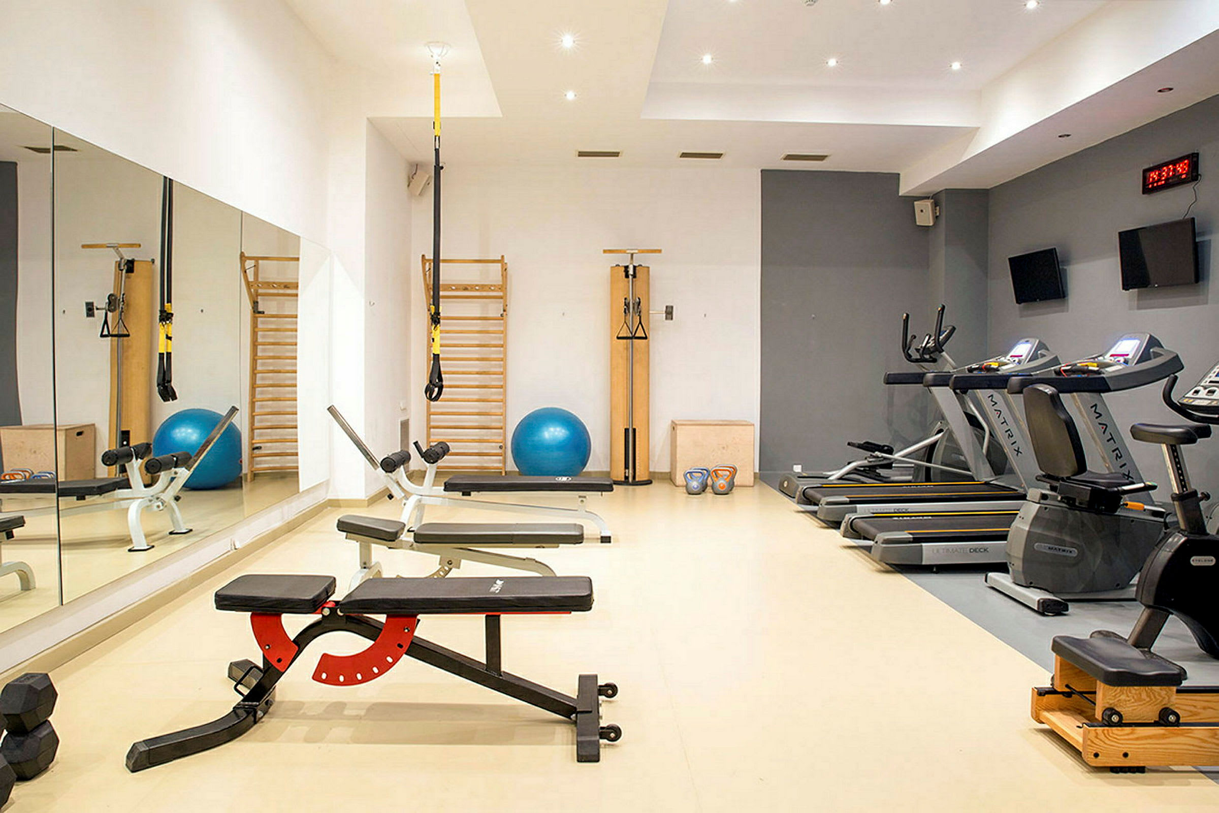 Ett gym med träningsredskap som löpband, träningsbänkar och träningsbollar. (AI-genererad text)