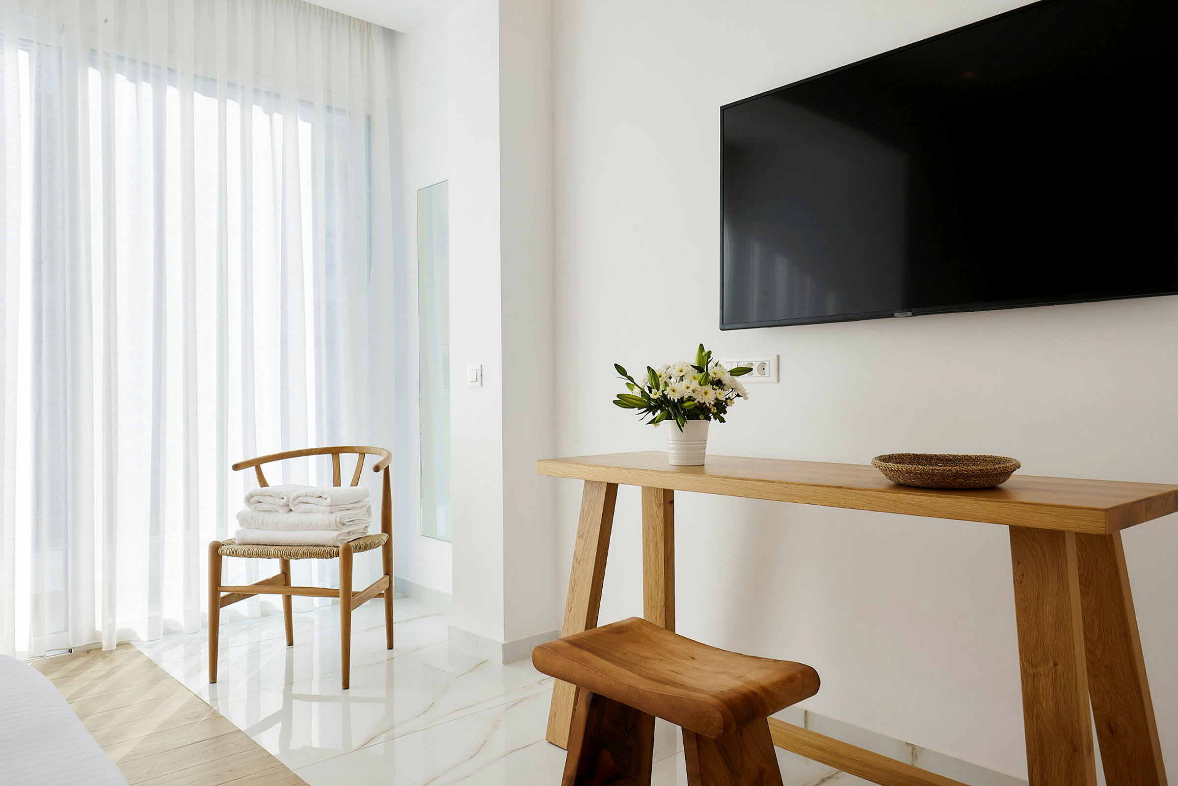 Interiör av ett modernt rum med träbord, trästol och en TV på väggen. (AI-genererad text)