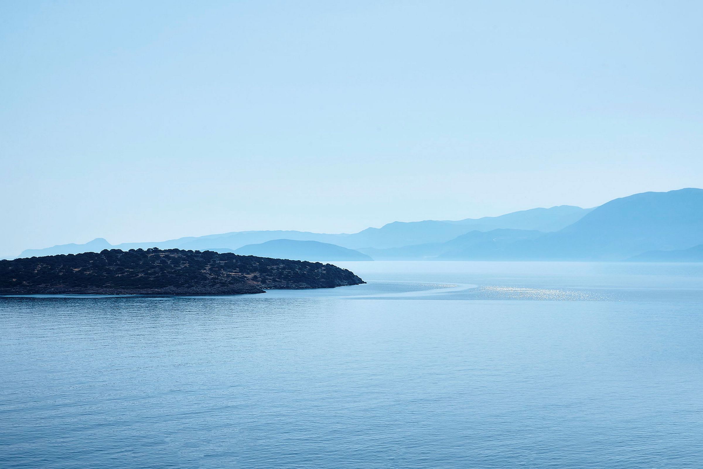 En vy över havet med en ö i förgrunden och berg i bakgrunden. (AI-genererad text)