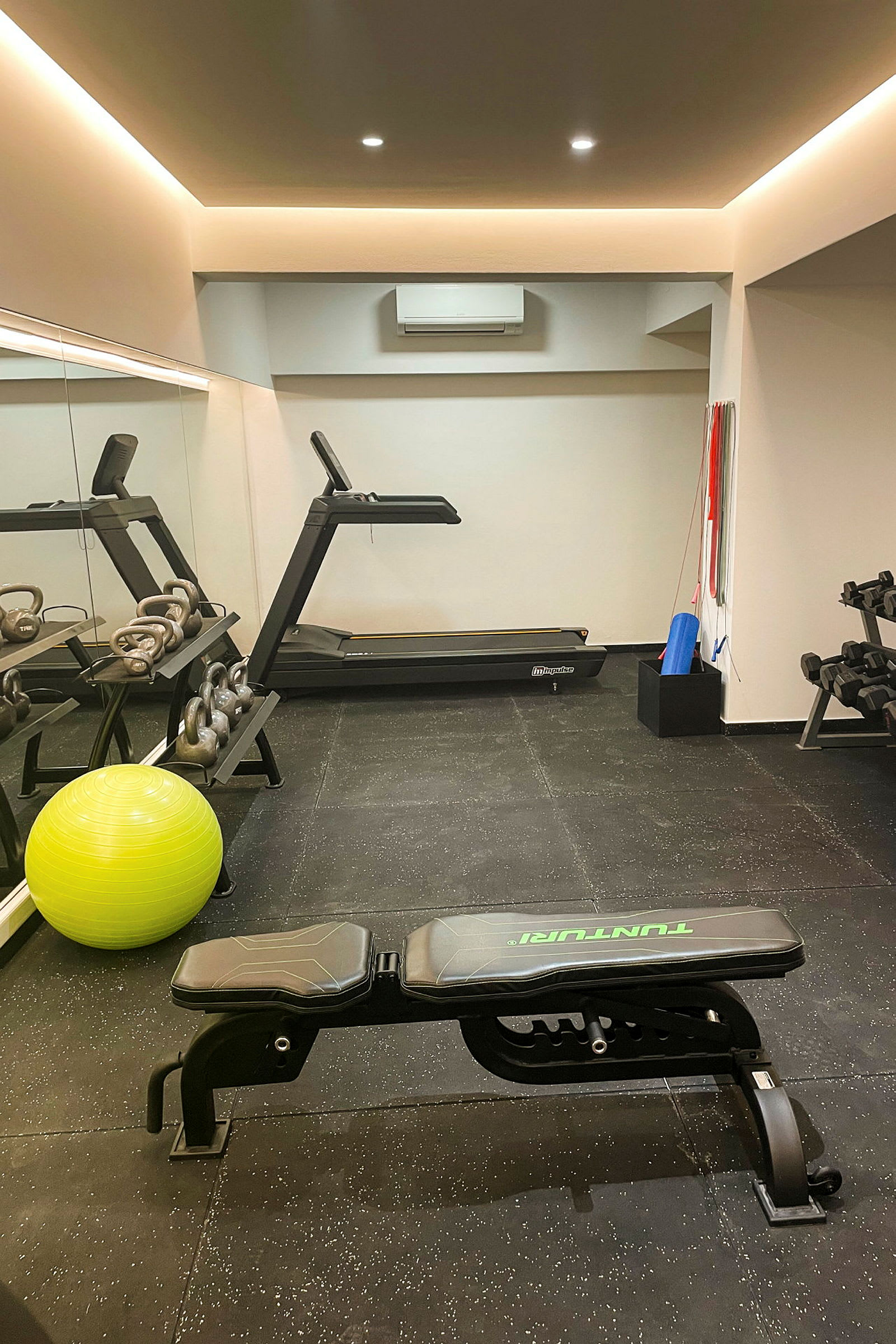 Ett gym med löpband, träningsbänk, kettlebells och pilatesboll. (AI-genererad text)