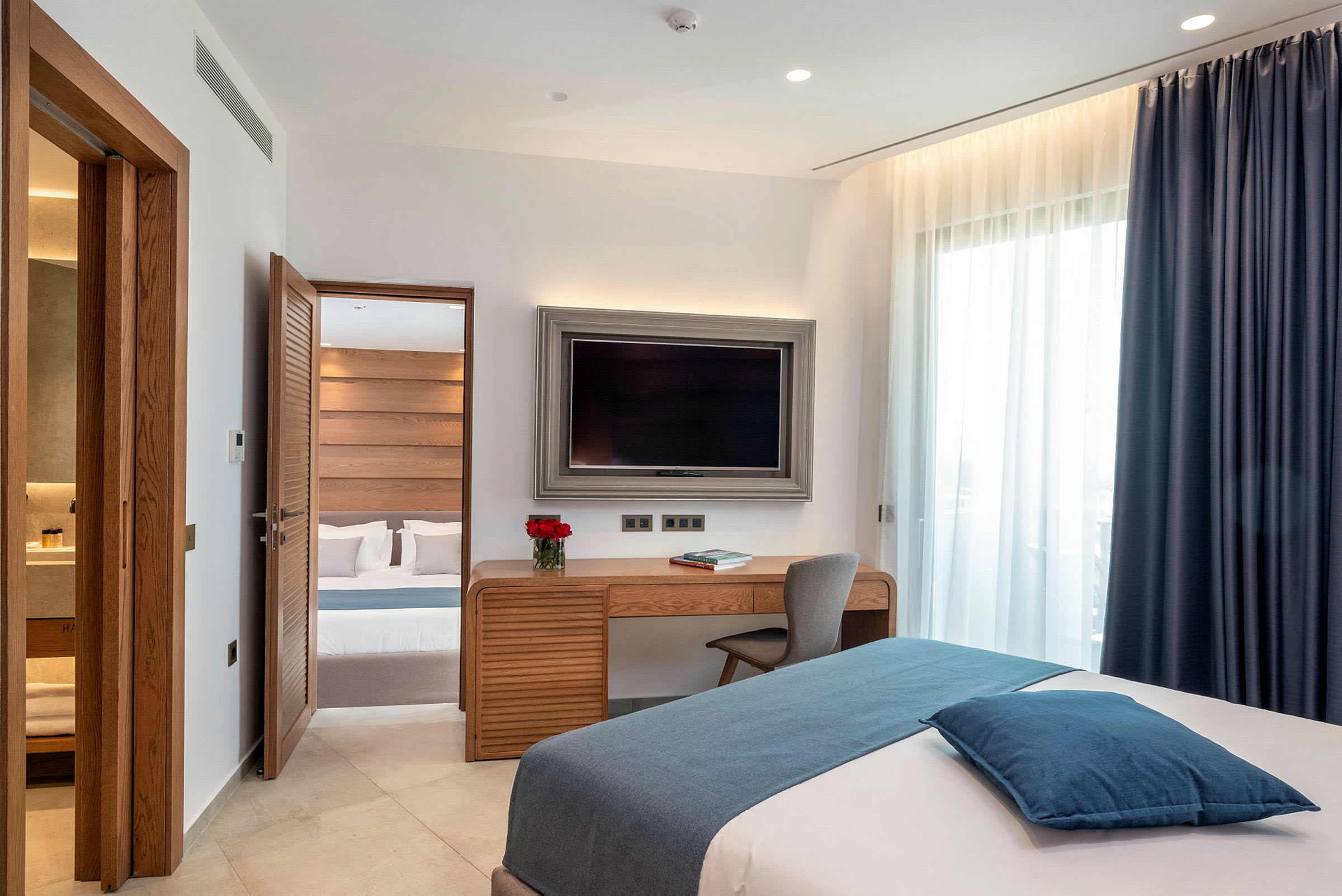 Ett hotellrum med modern inredning, en säng, ett skrivbord och en TV. (AI-genererad text)