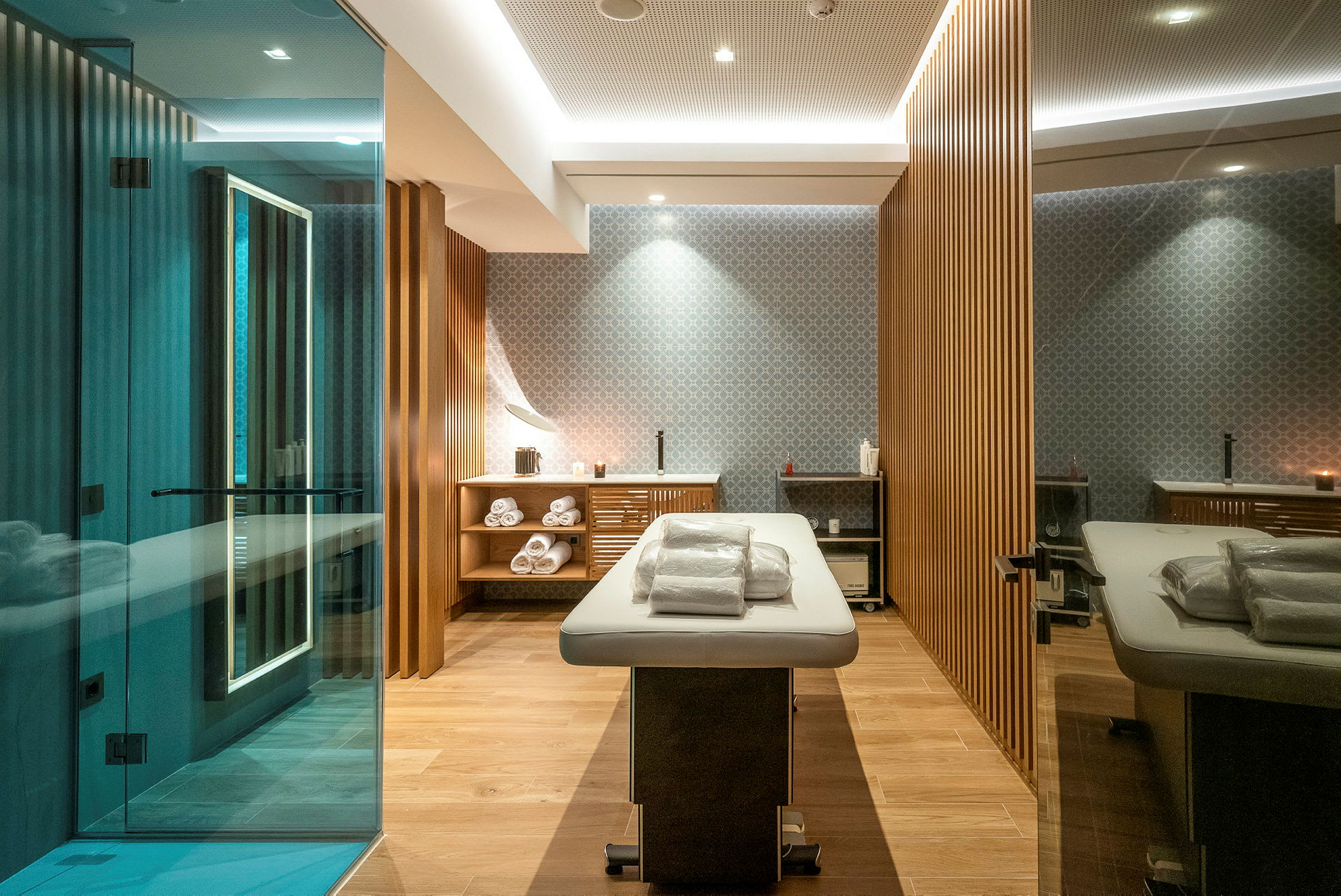 Ett modernt spa-rum med en massagebänk, handdukar och trädetaljer. (AI-genererad text)