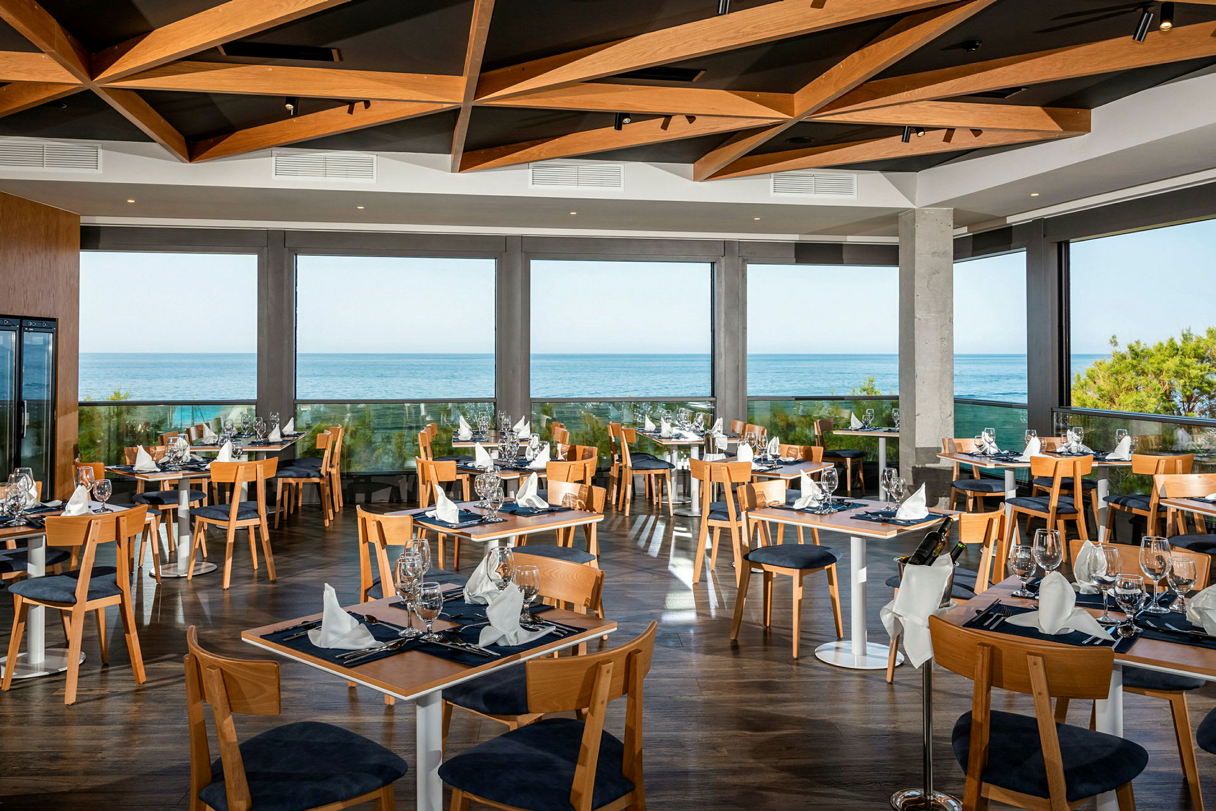En modern restaurang med stora glasfönster och havsutsikt. (AI-genererad text)