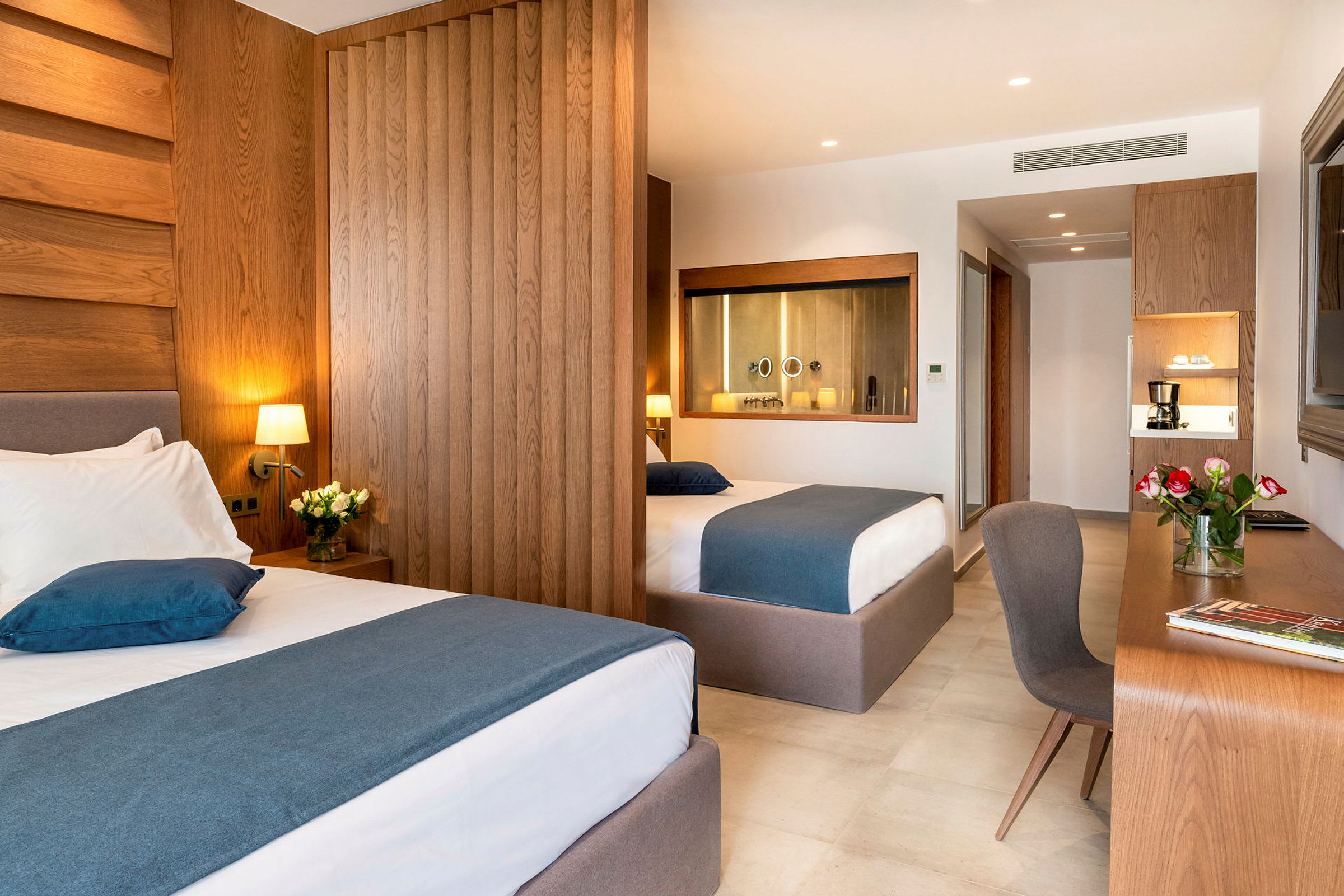 Ett hotellrum med två sängar, skrivbord och blommor. (AI-genererad text)