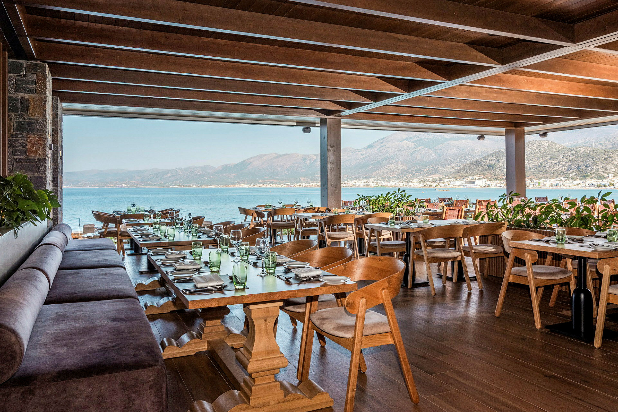 En restaurang med träbord och stolar samt sjöutsikt. (AI-genererad text)