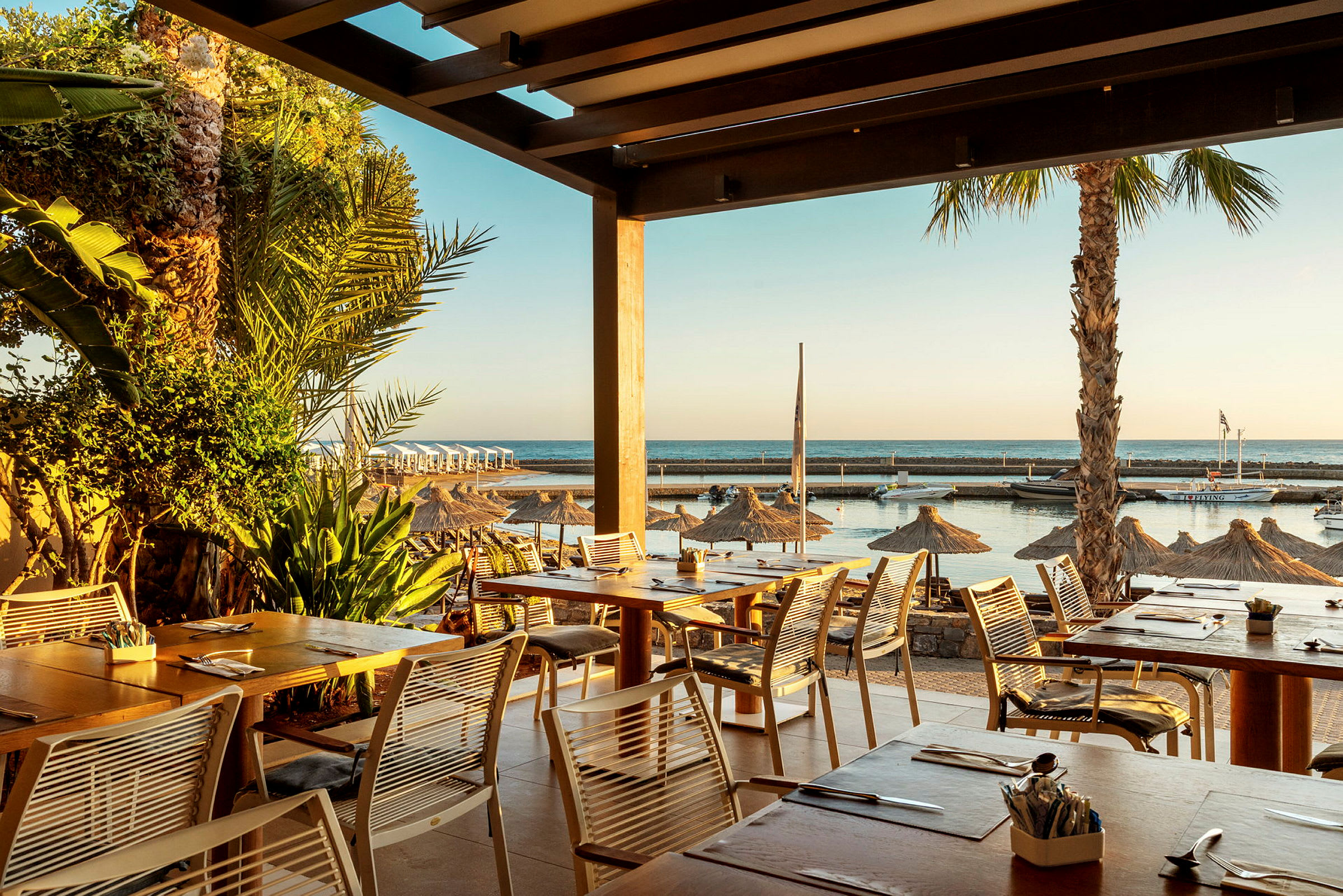 Utsikt från en restaurang med havet i bakgrunden och parasoll på stranden. (AI-genererad text)