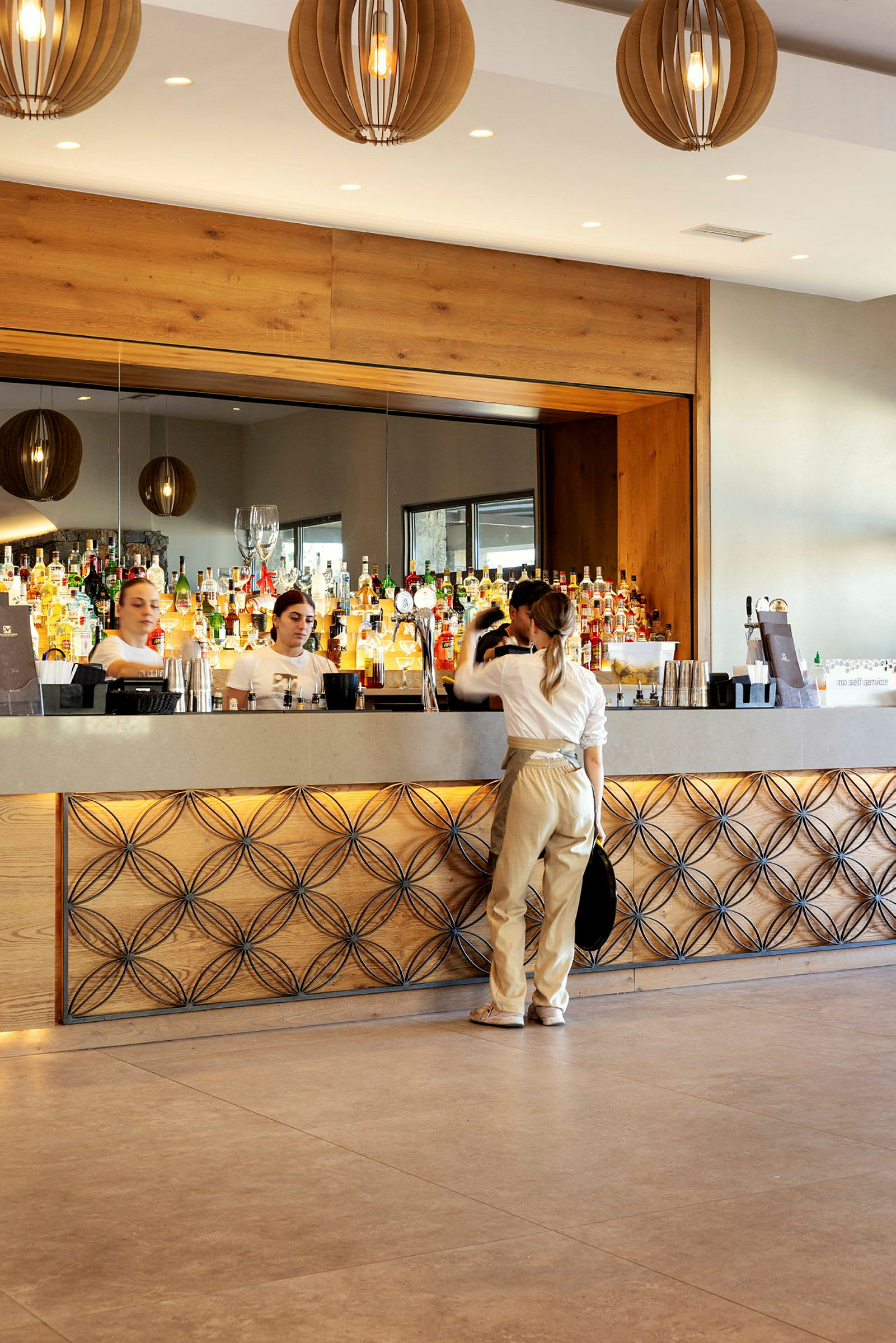 En bartender och kunder vid en elegant bar med flaskor och glas i bakgrunden. (AI-genererad text)