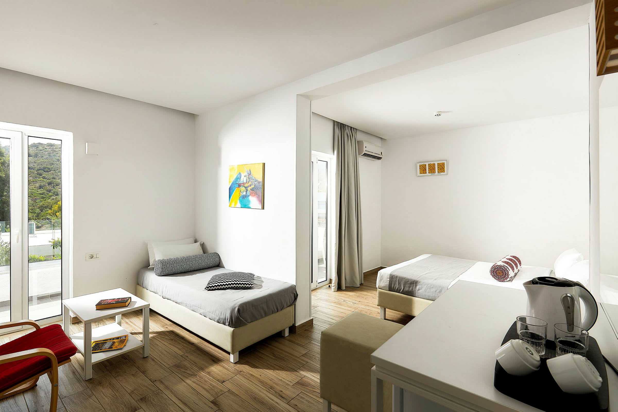 Bild av ett hotellrum med två enkelsängar, ljusa väggar och möbler samt ett bord med elektroniska faciliteter. (AI-genererad text)