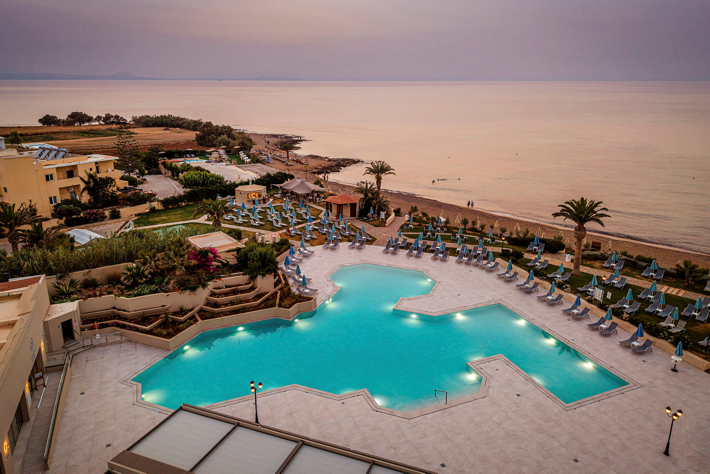 Hotellområde med stor pool, solstolar och havet i bakgrunden. (AI-genererad text)