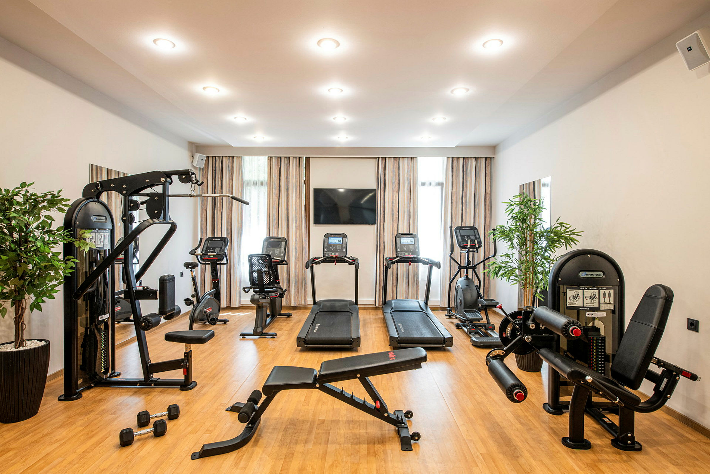 Ett gym med träningsmaskiner, löpband och träningsbänkar i en ljus och modern lokal. (AI-genererad text)