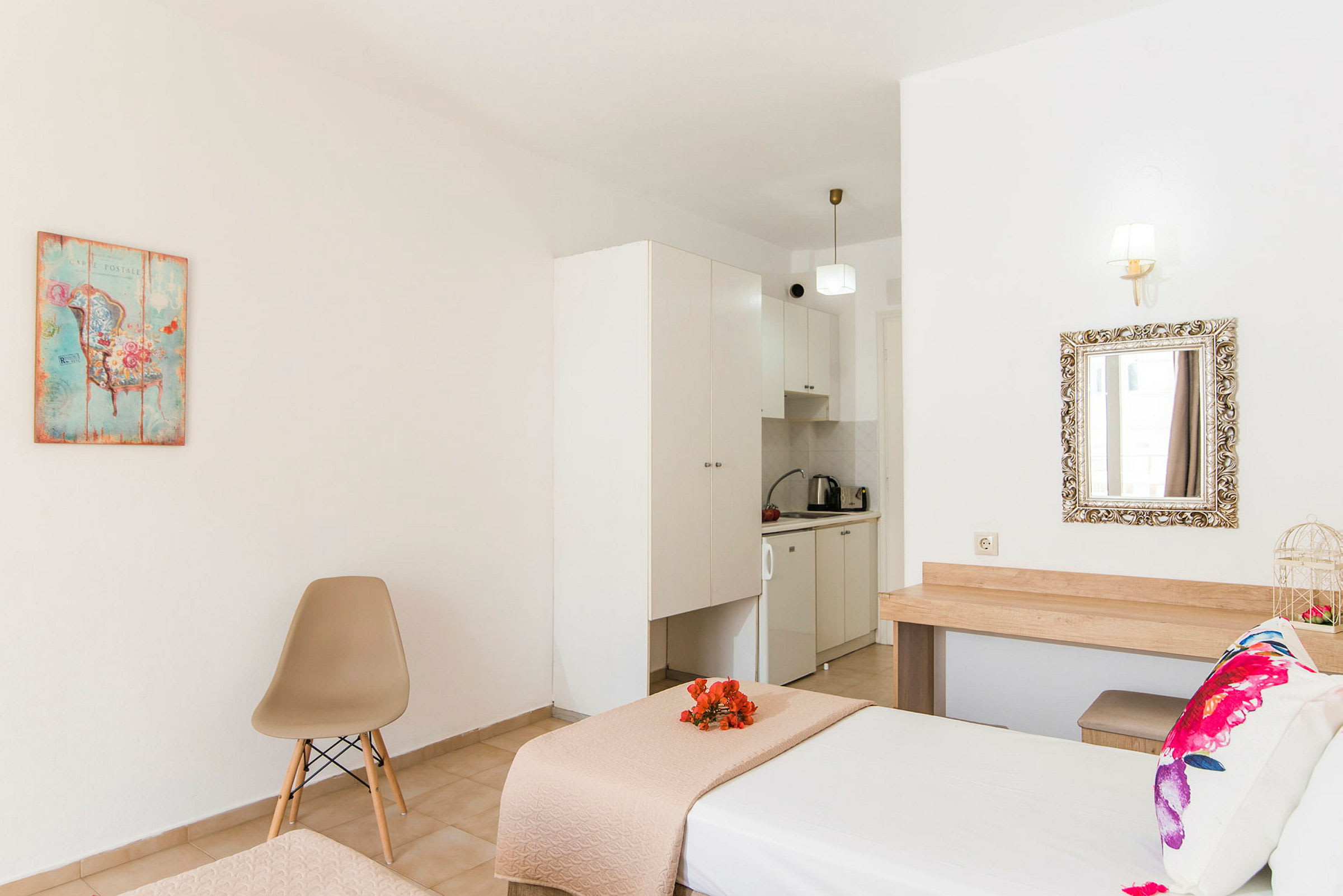 Ett hotellrum med säng, stol, bildekorativ tavla och ett litet köksområde. (AI-genererad text)