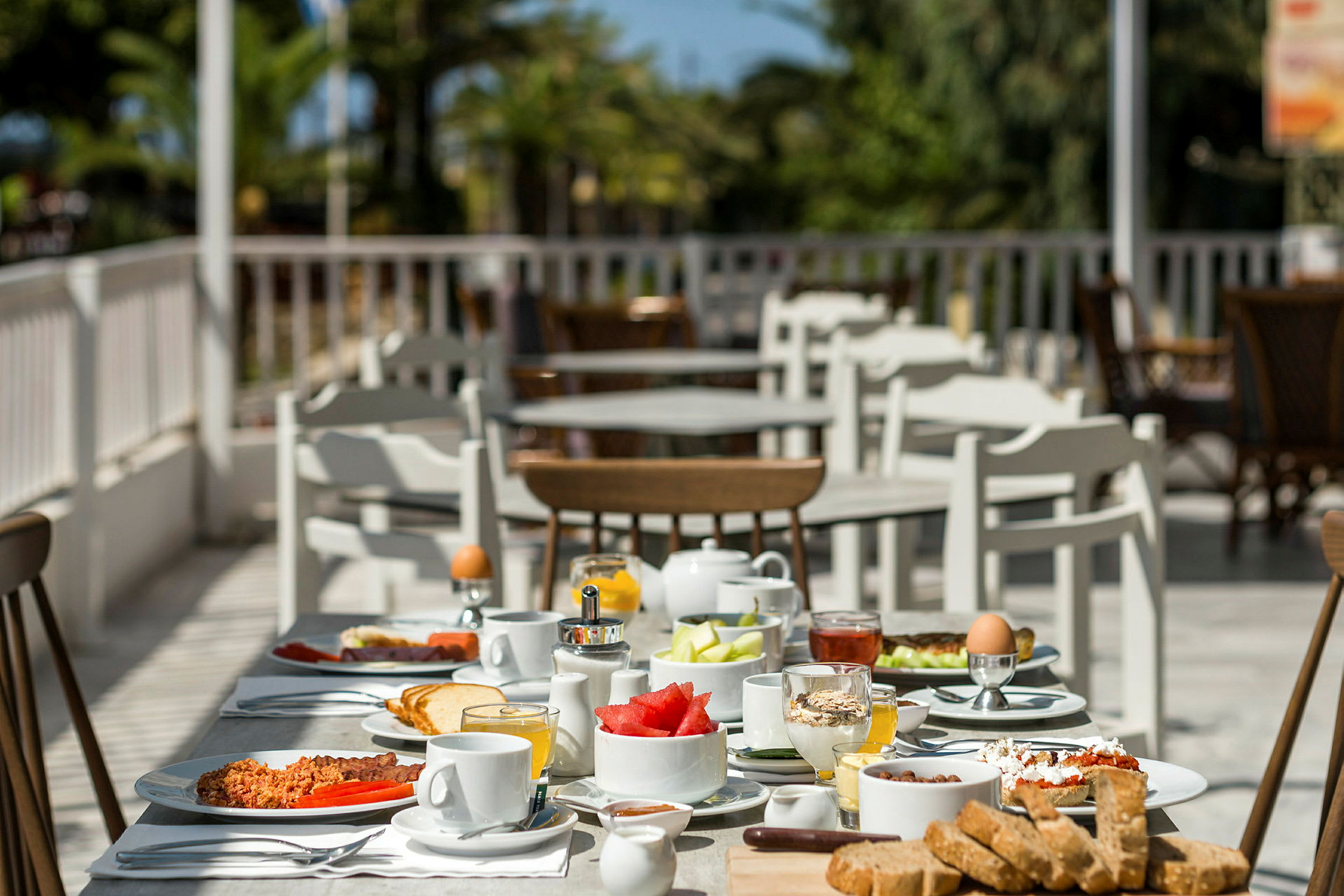 Ett bord fyllt med frukostmat, med fler bord och stolar i bakgrunden. (AI-genererad text)