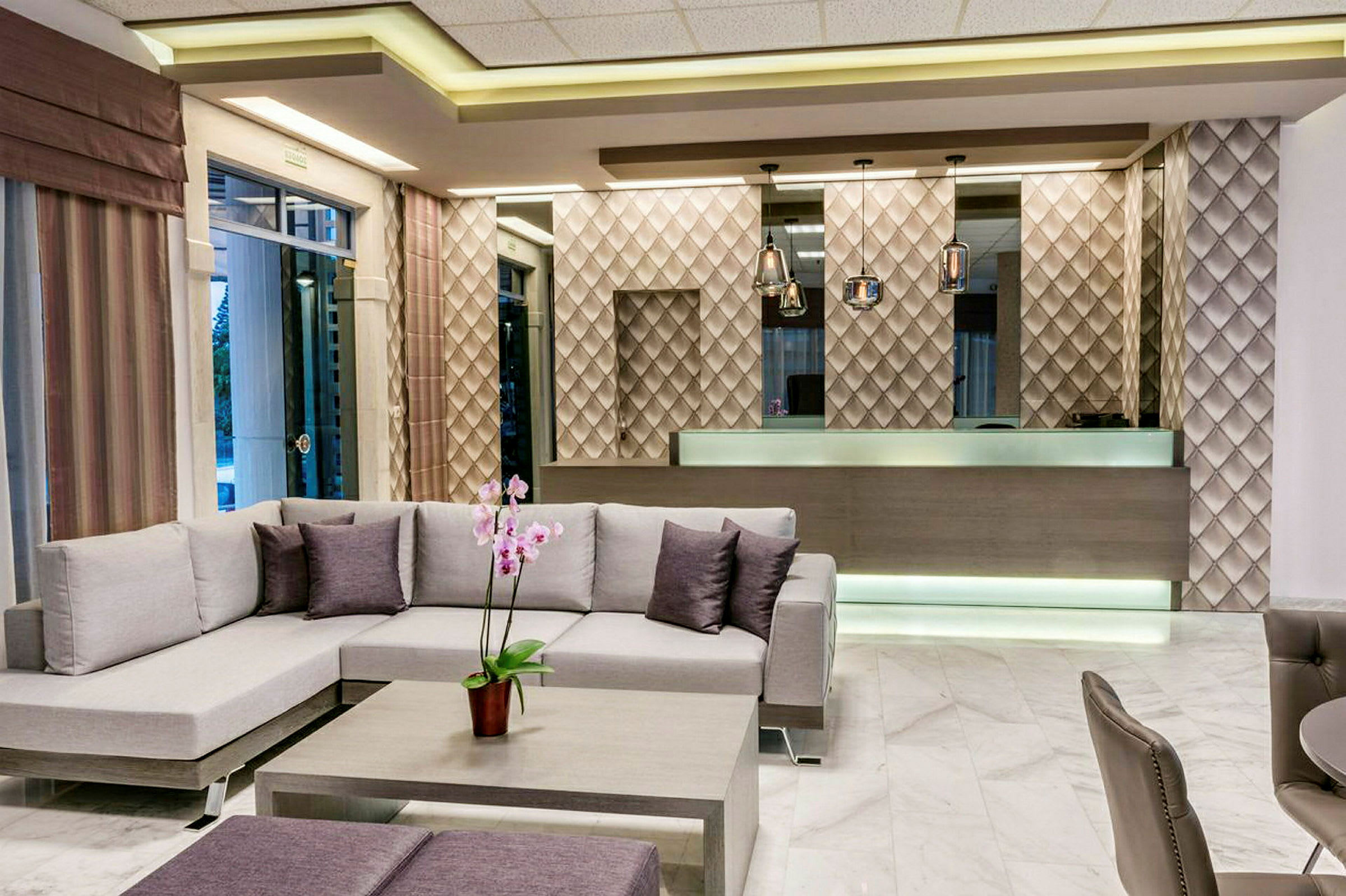 Hotellobbyn med modern inredning, inklusive en soffa och ett receptionsområde som har en designad vägg med lampor. (AI-genererad text)
