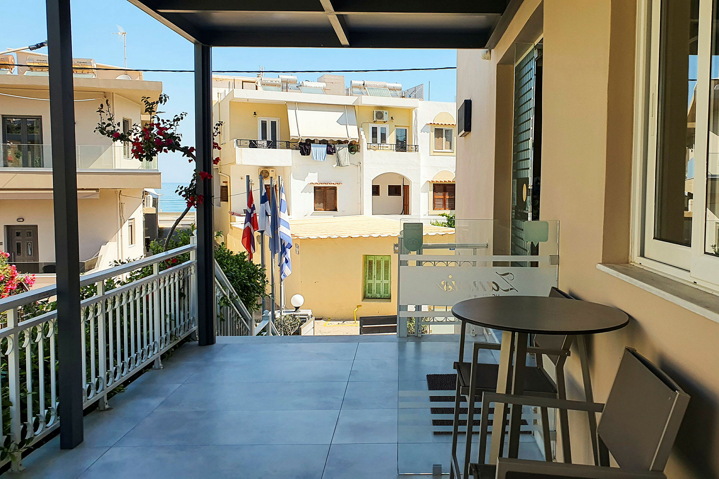 En veranda med stolar och bord, utsikt över bostadshus och några flaggor. (AI-genererad text)