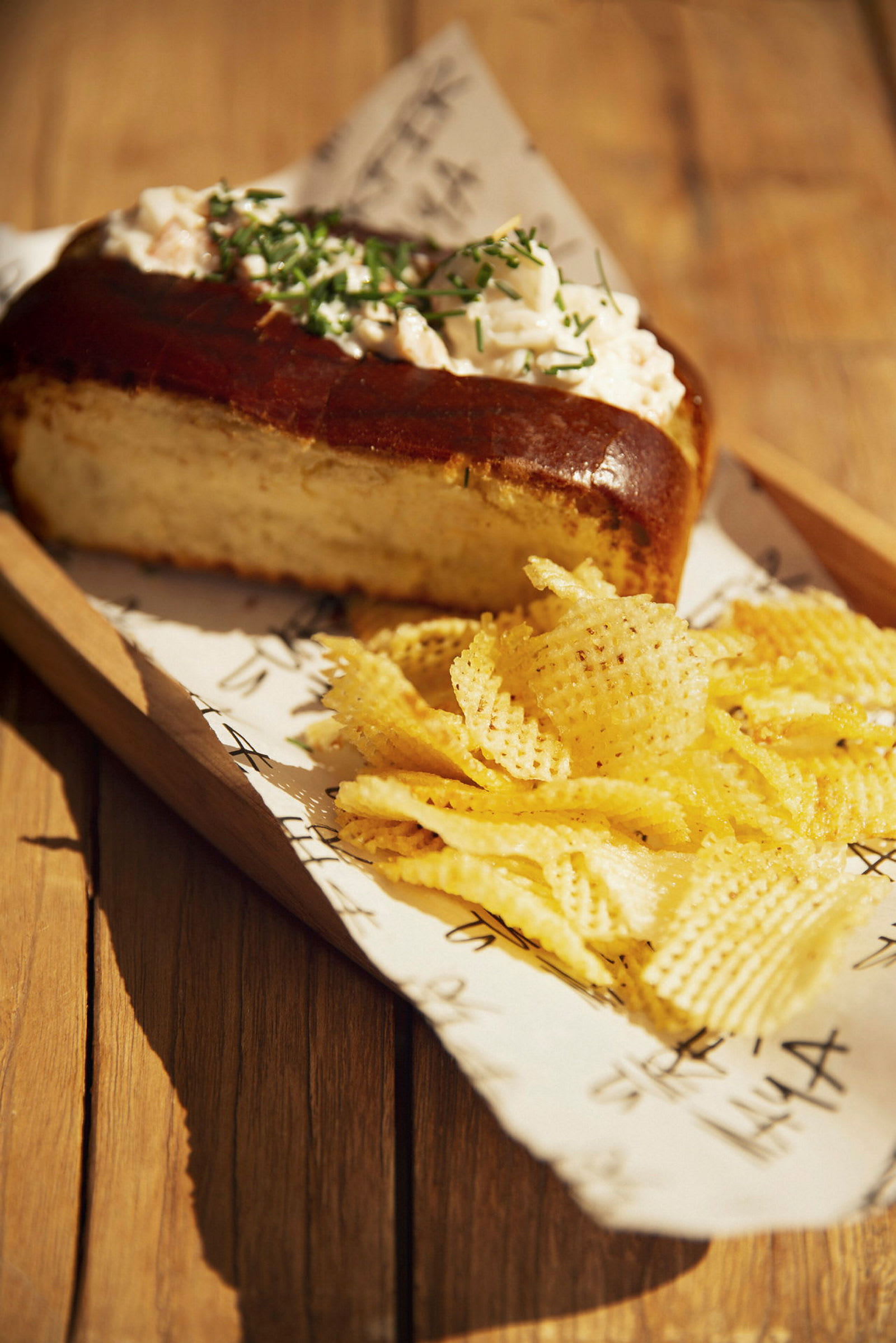 Bröd med topping och chips på ett träbord. (AI-genererad text)