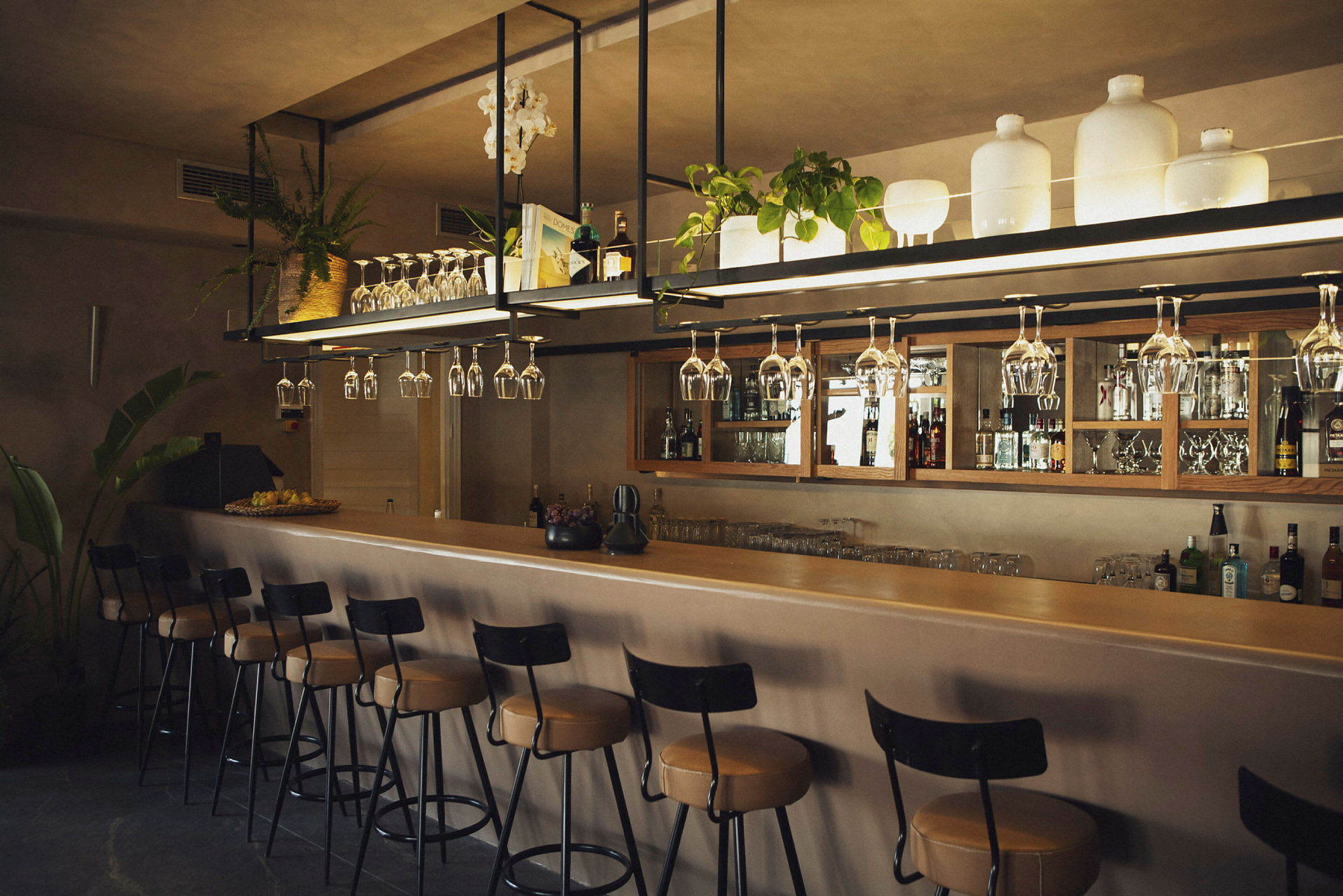 En bar med upphängda vinglas, stolar och förvaringsytor. (AI-genererad text)