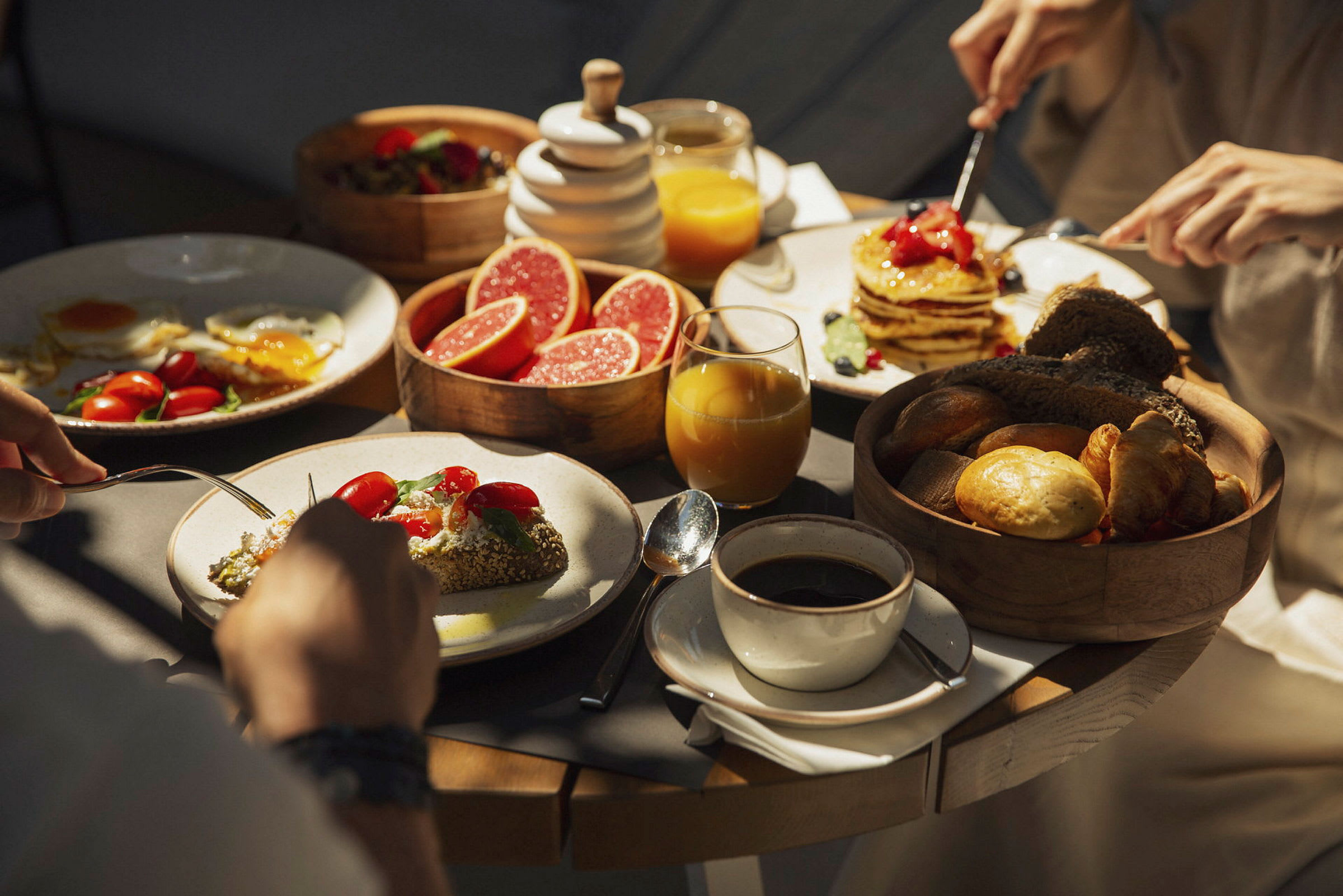 En frukost med diverse mat, inklusive pannkakor, grapefruktskivor, bröd och kaffe. (AI-genererad text)