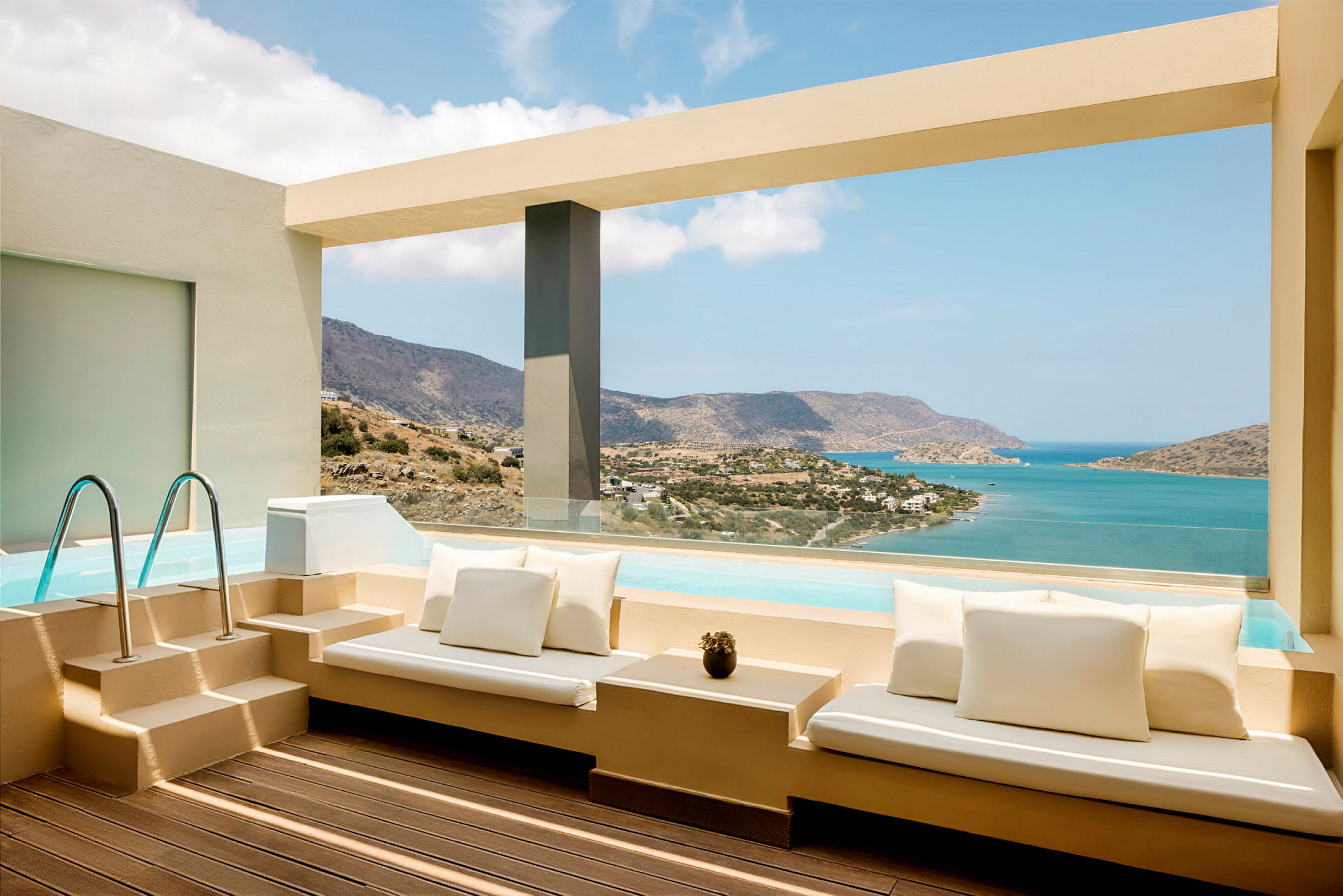Terrass med sittplatser vid pool med utsikt över havet och berg. (AI-genererad text)