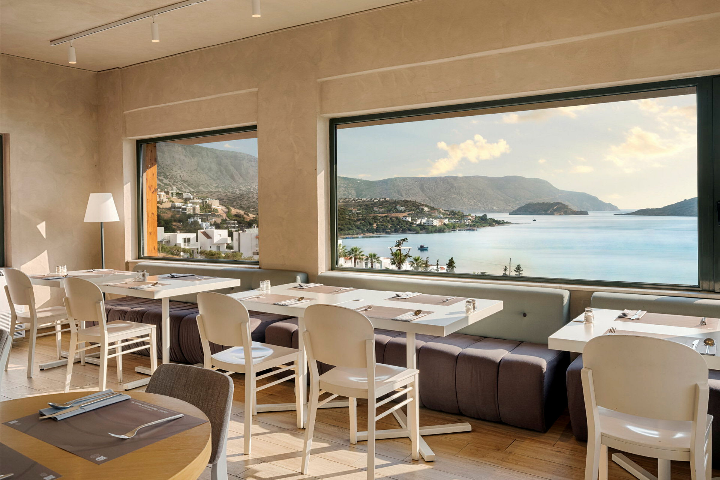 Restaurang med dukade bord och panoramautsikt över kust och berg. (AI-genererad text)