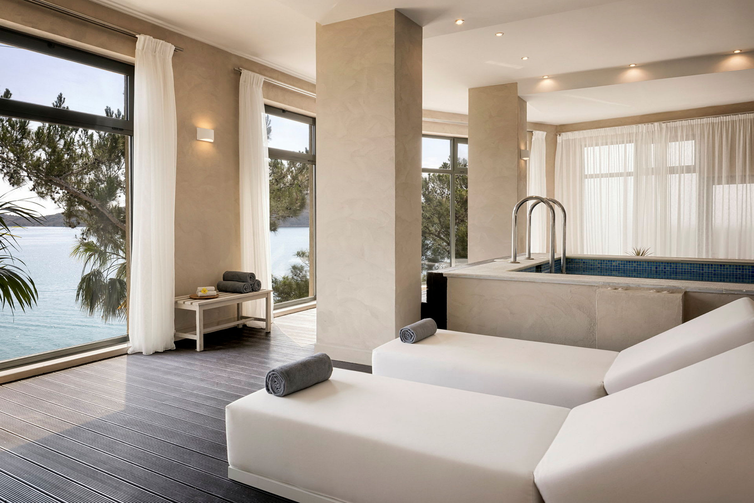 Ett modernt spa med vilstolar och en inomhuspool med utsikt mot havet. (AI-genererad text)