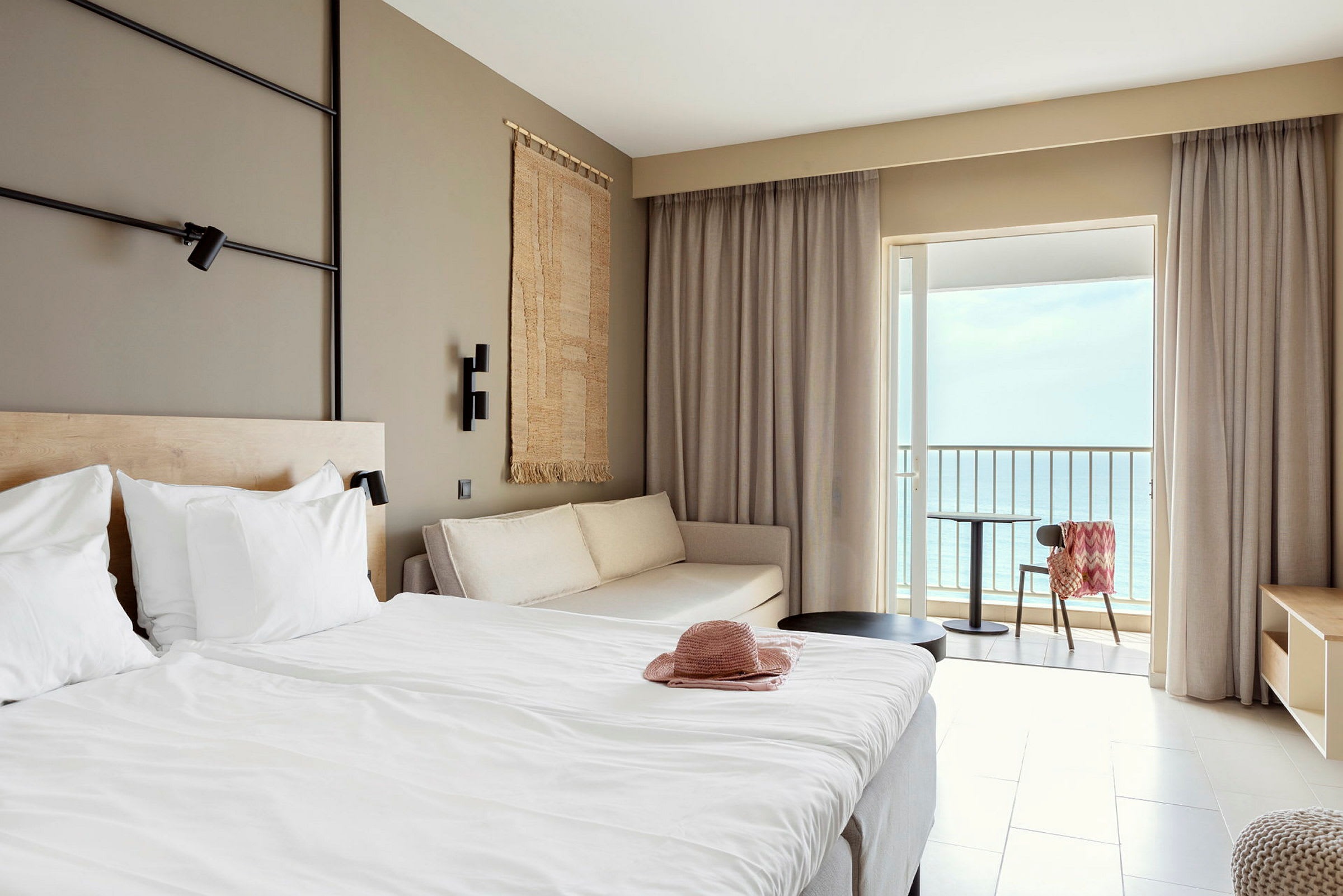 Hotellrum med säng, soffa och balkong med havsutsikt. (AI-genererad text)