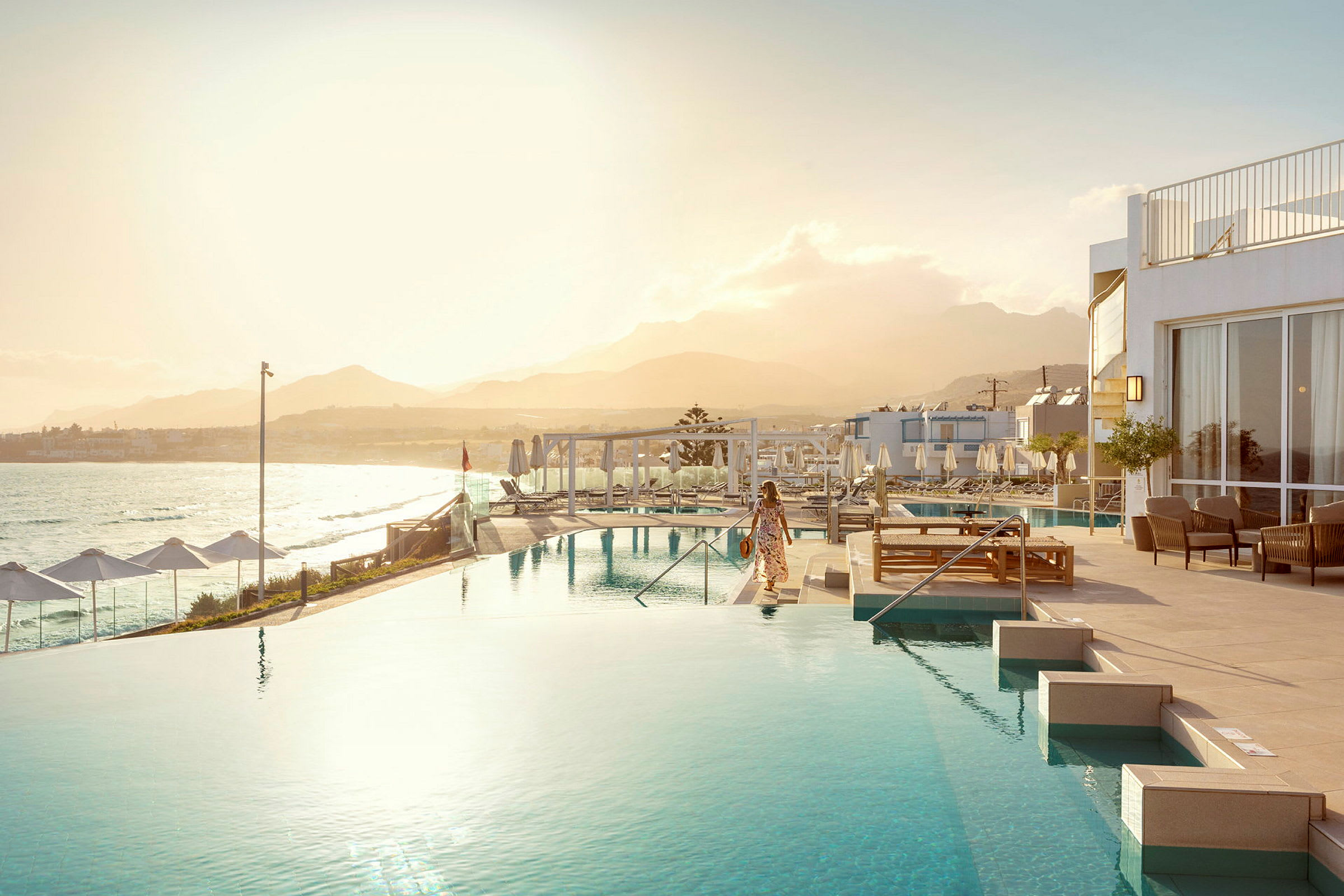 En kvinna vid en infinitypool med havet och en bergskedja i bakgrunden. (AI-genererad text)