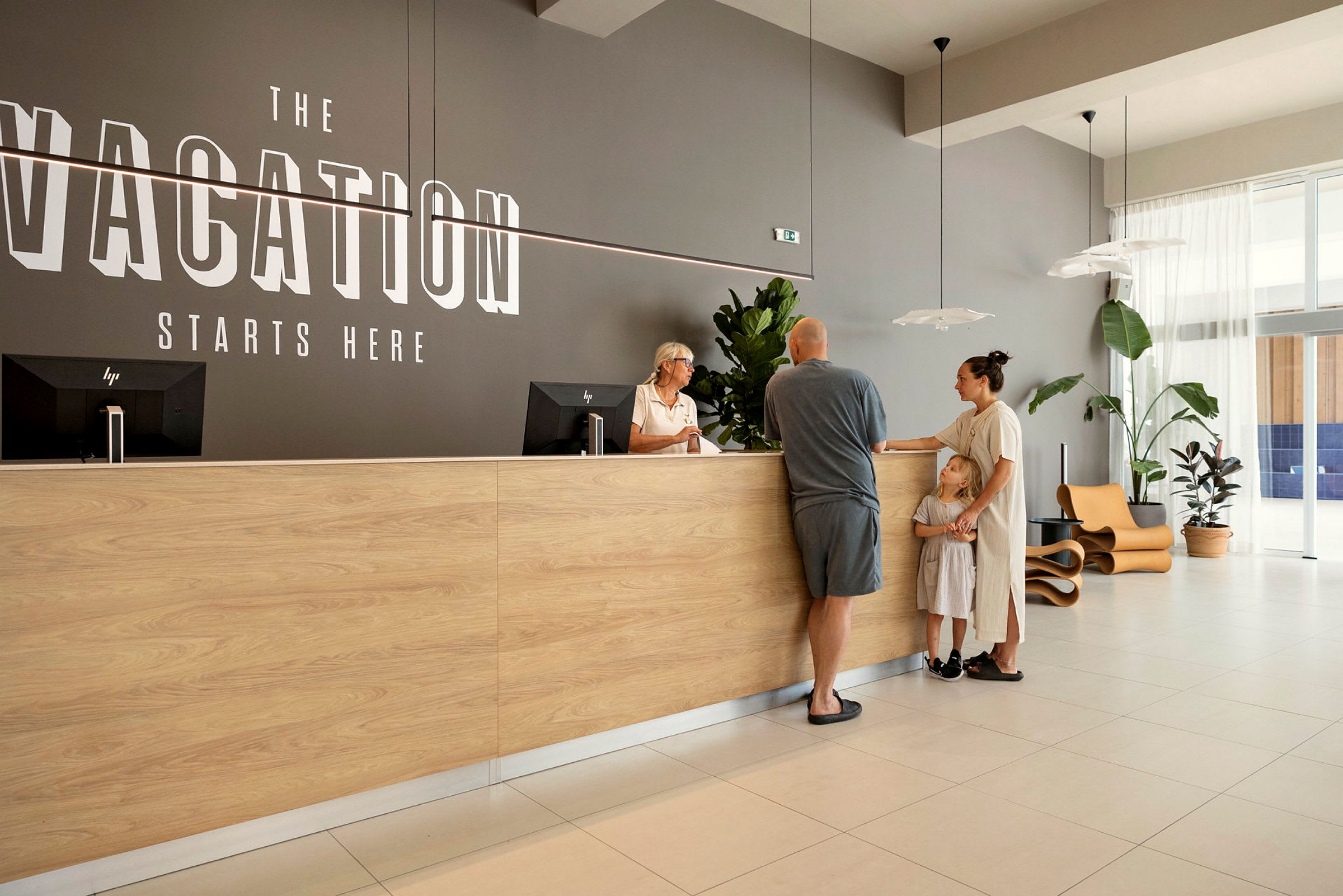 En reception med en trädisk och texten "Vacation Starts Here" på väggen. (AI-genererad text)