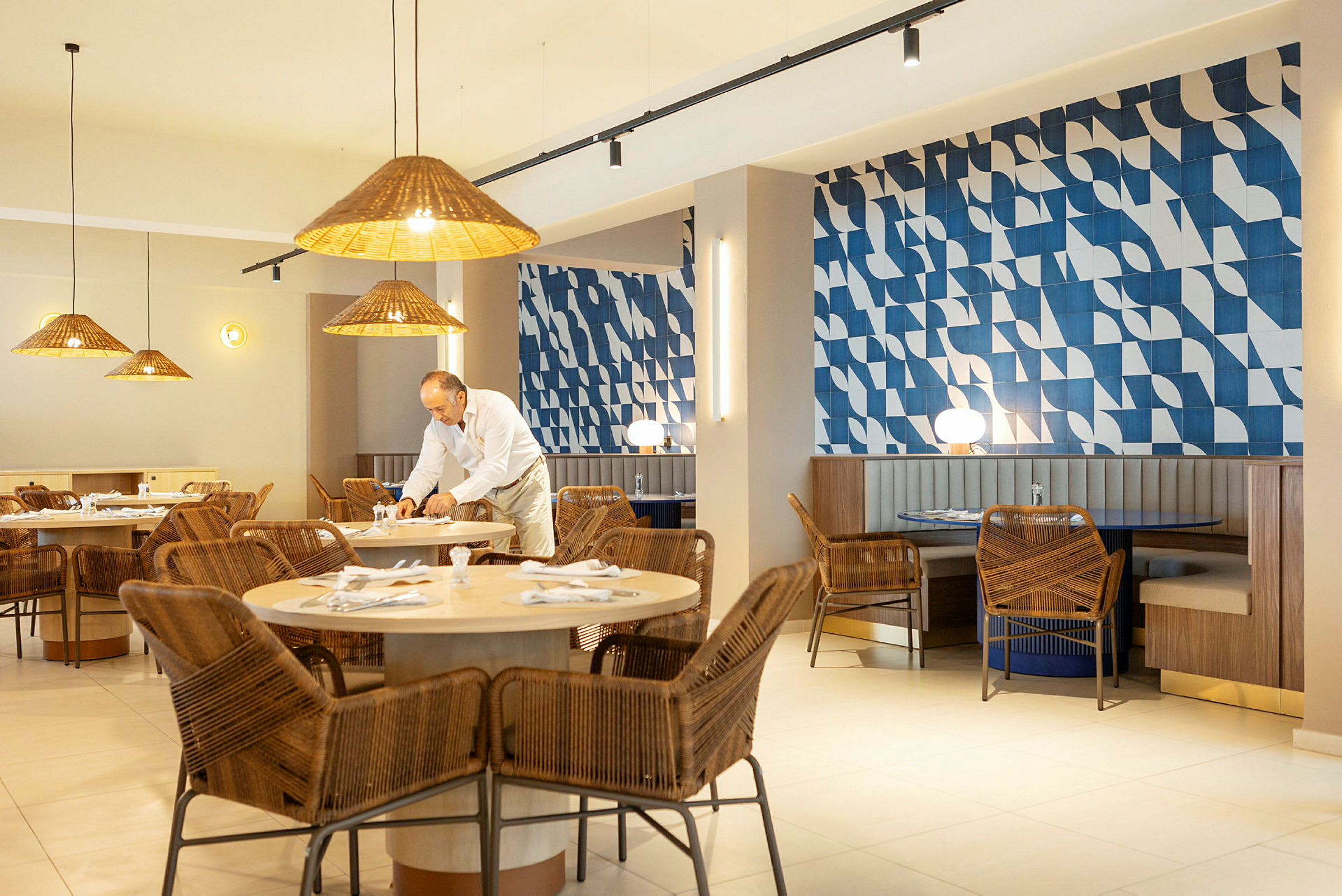 Restaurang med rottingstolar och blåmönstrad vägg. (AI-genererad text)