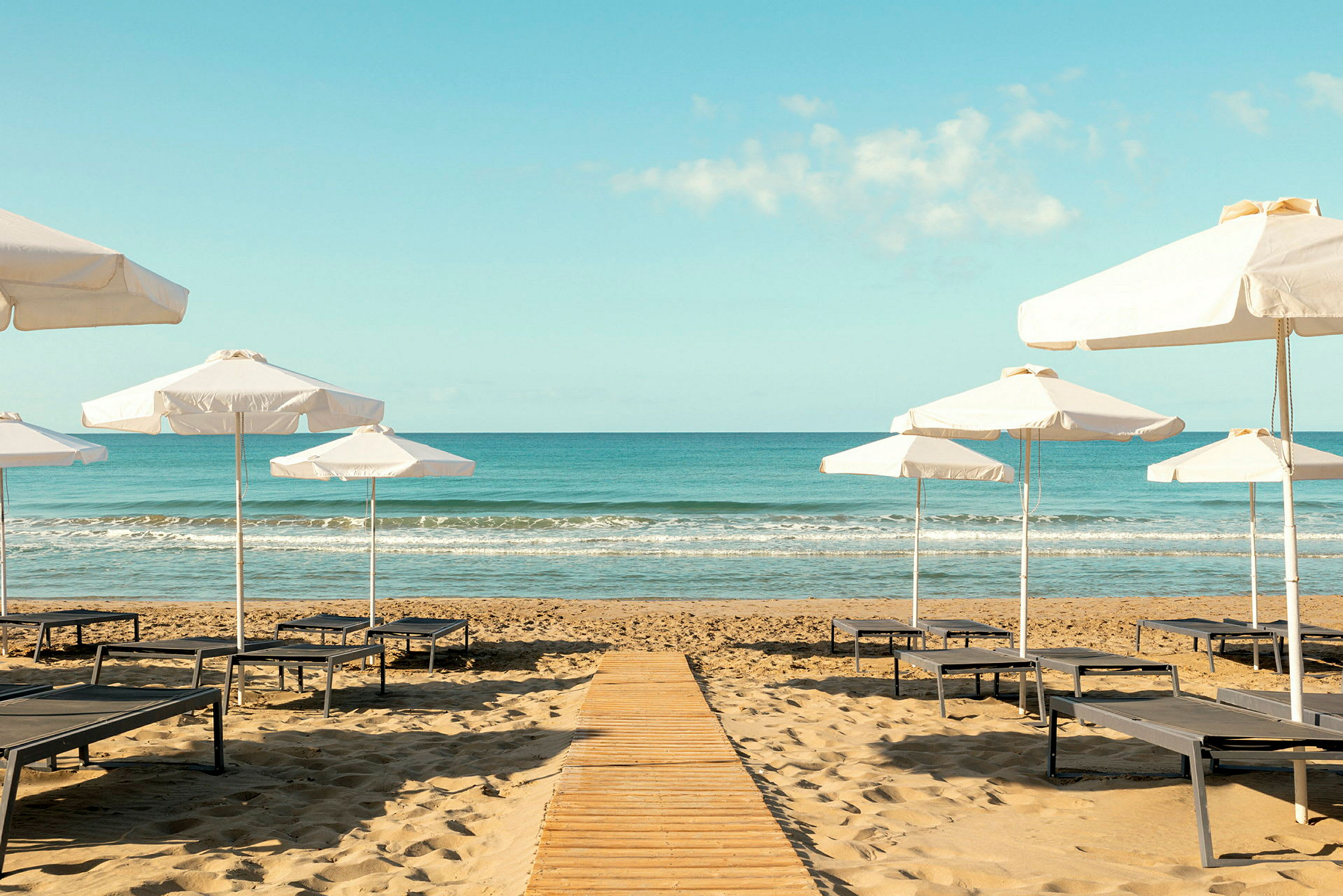 Strand med parasoller och solstolar vid havet. (AI-genererad text)