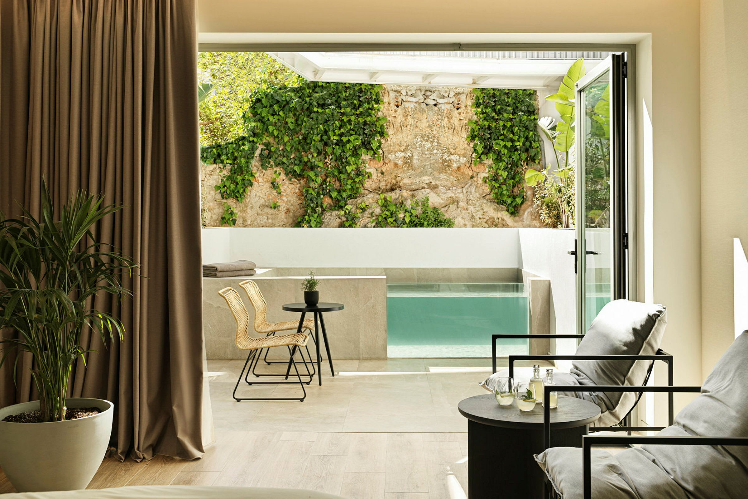 Modernt rum med sittgrupp och utsikt över privat pool och vägg med klätterväxt. (AI-genererad text)