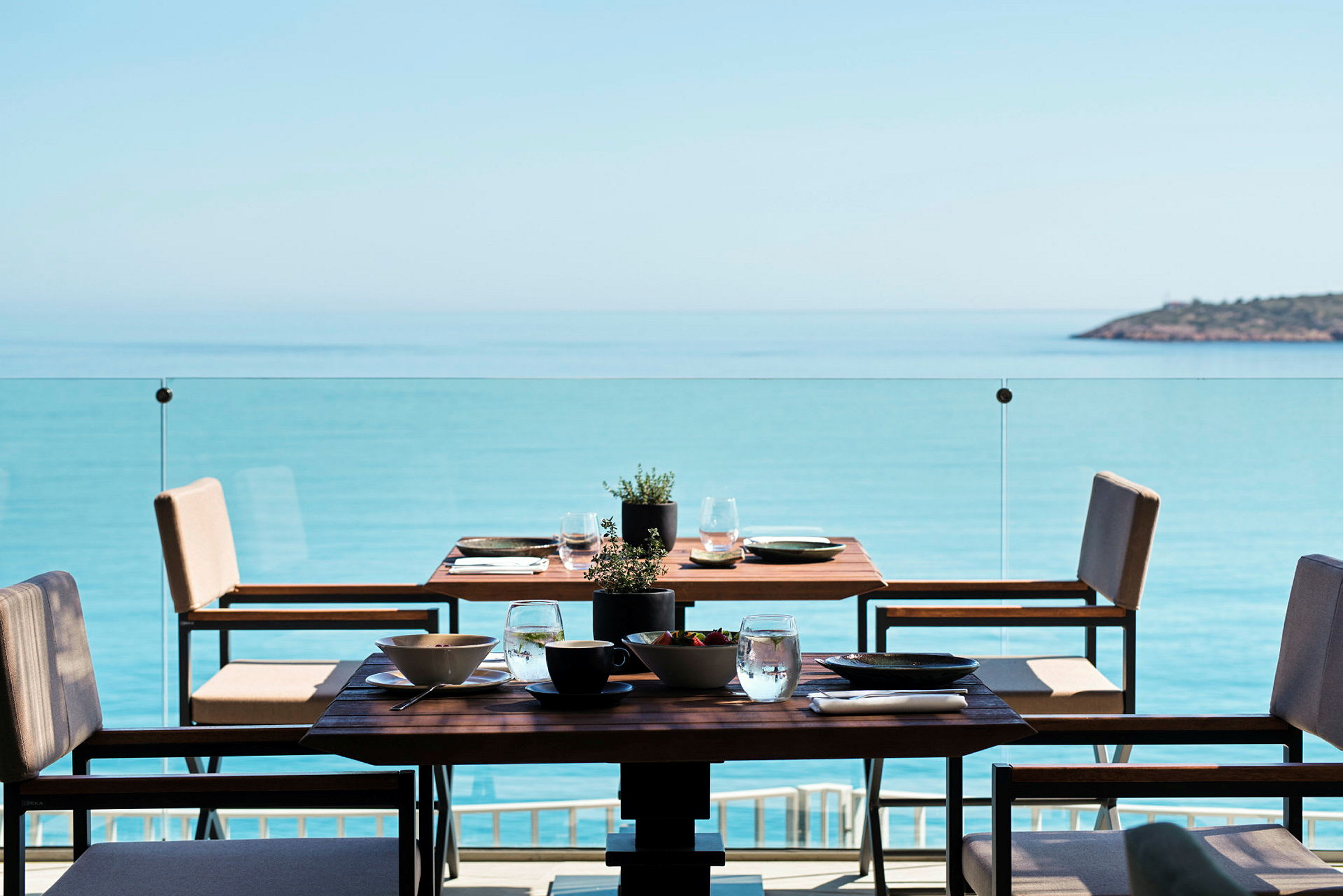 Ett dukat bord på en terrass med utsikt över havet. (AI-genererad text)