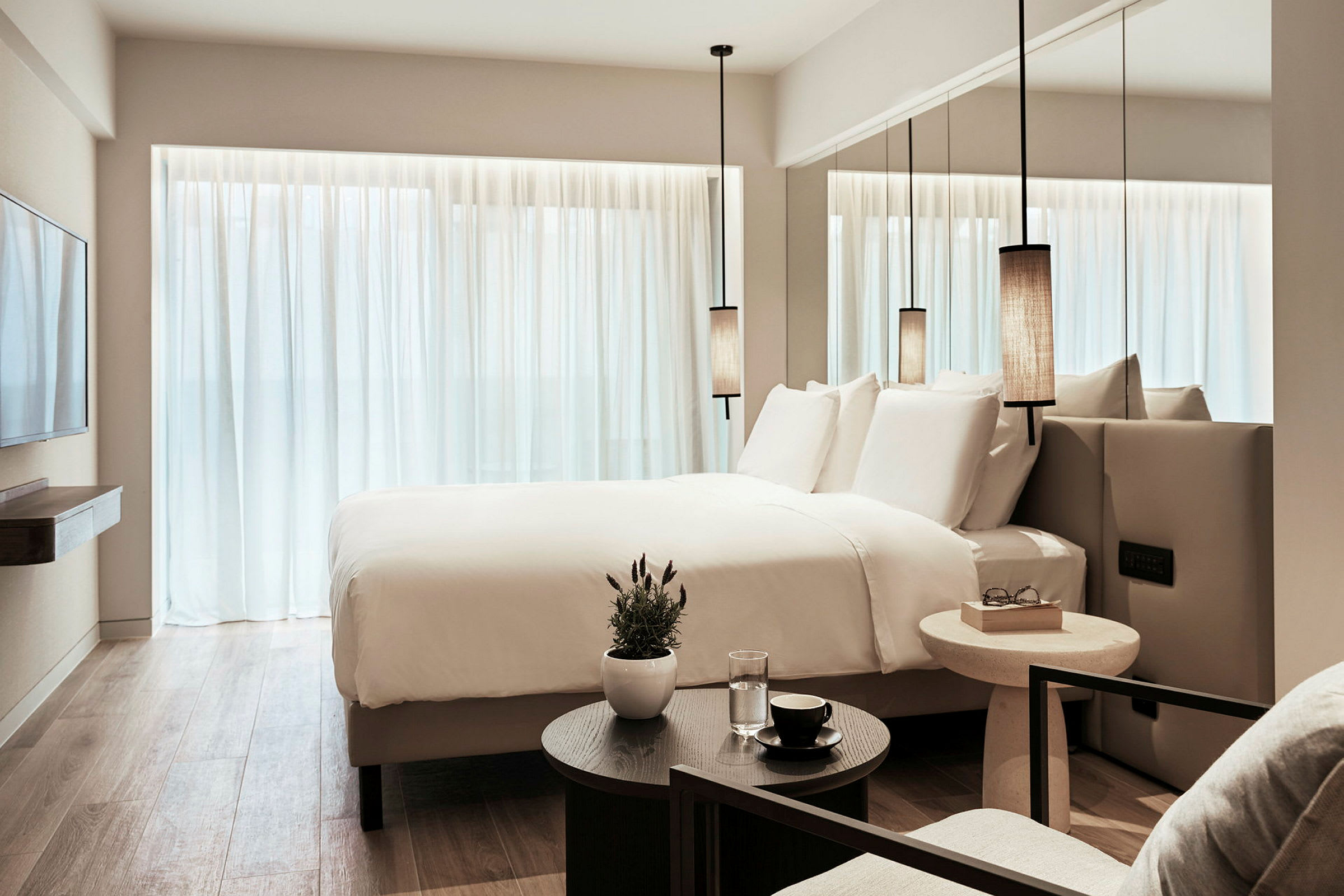 Ett modernt hotellrum med en stor säng, vita lakan och minimalistisk inredning. (AI-genererad text)