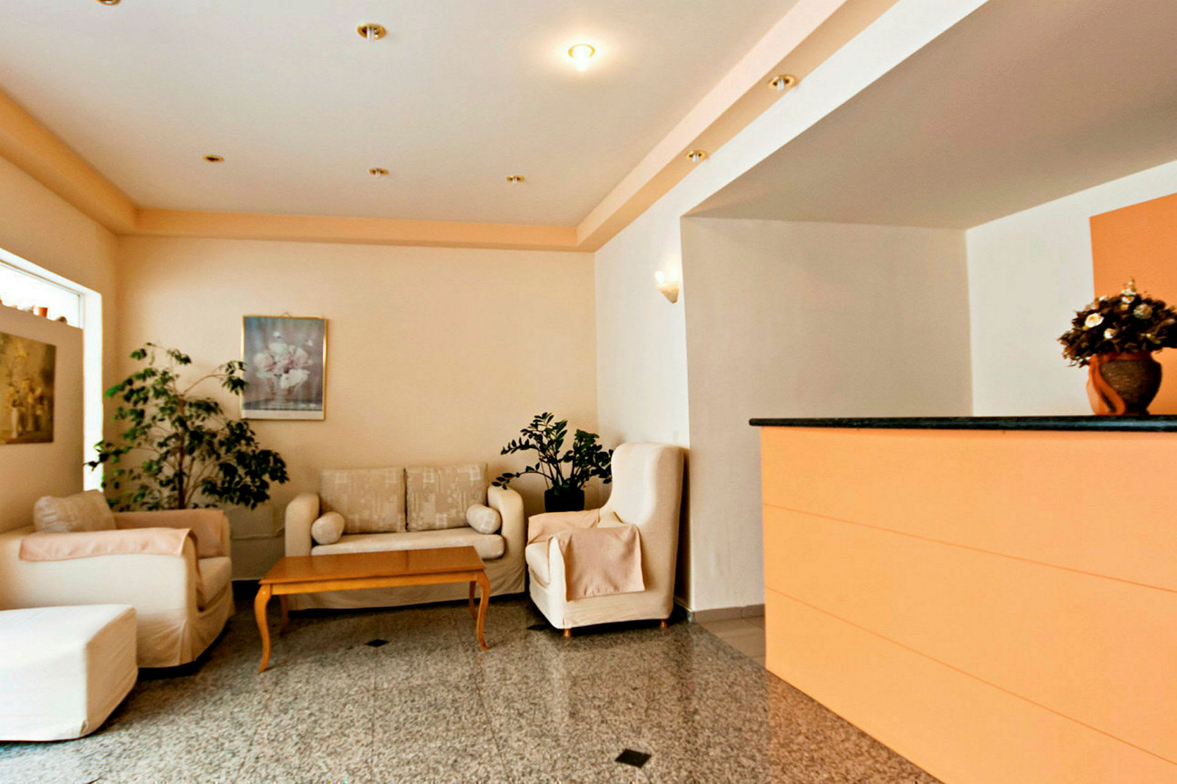 Lobbyområde med soffor, bord, dekorativa växter och en reception. (AI-genererad text)