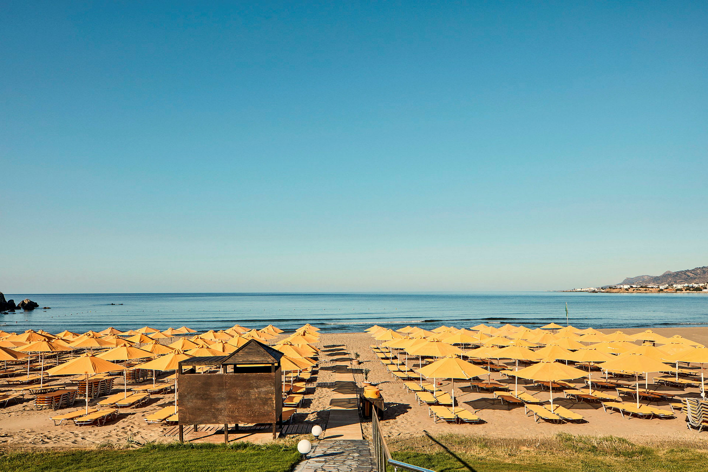 Strand med gula parasoller och solstolar framför havet. (AI-genererad text)
