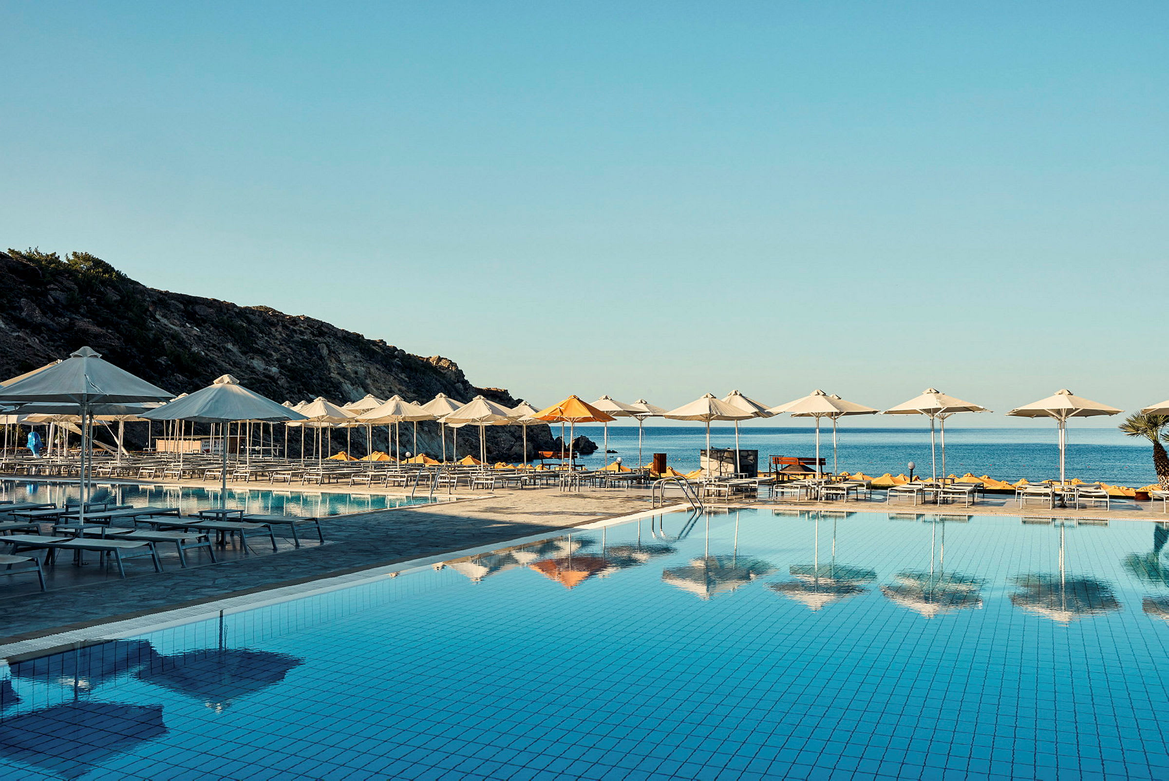 Swimmingpool områden med parasoller framför havet. (AI-genererad text)