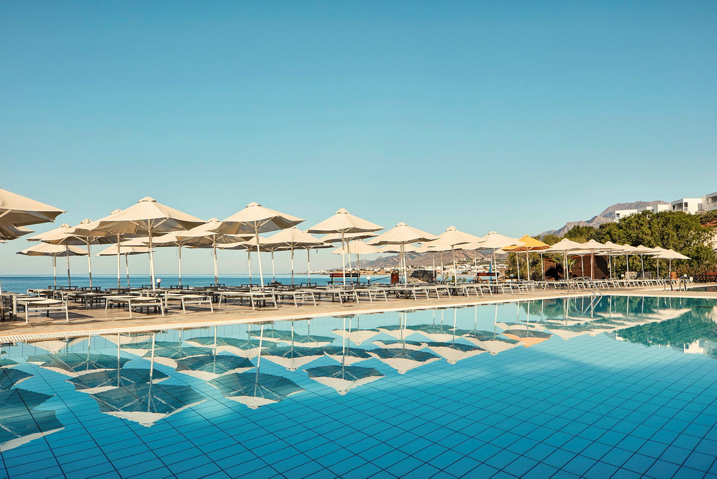Solstolar och parasoll vid en pool med utsikt över havet. (AI-genererad text)