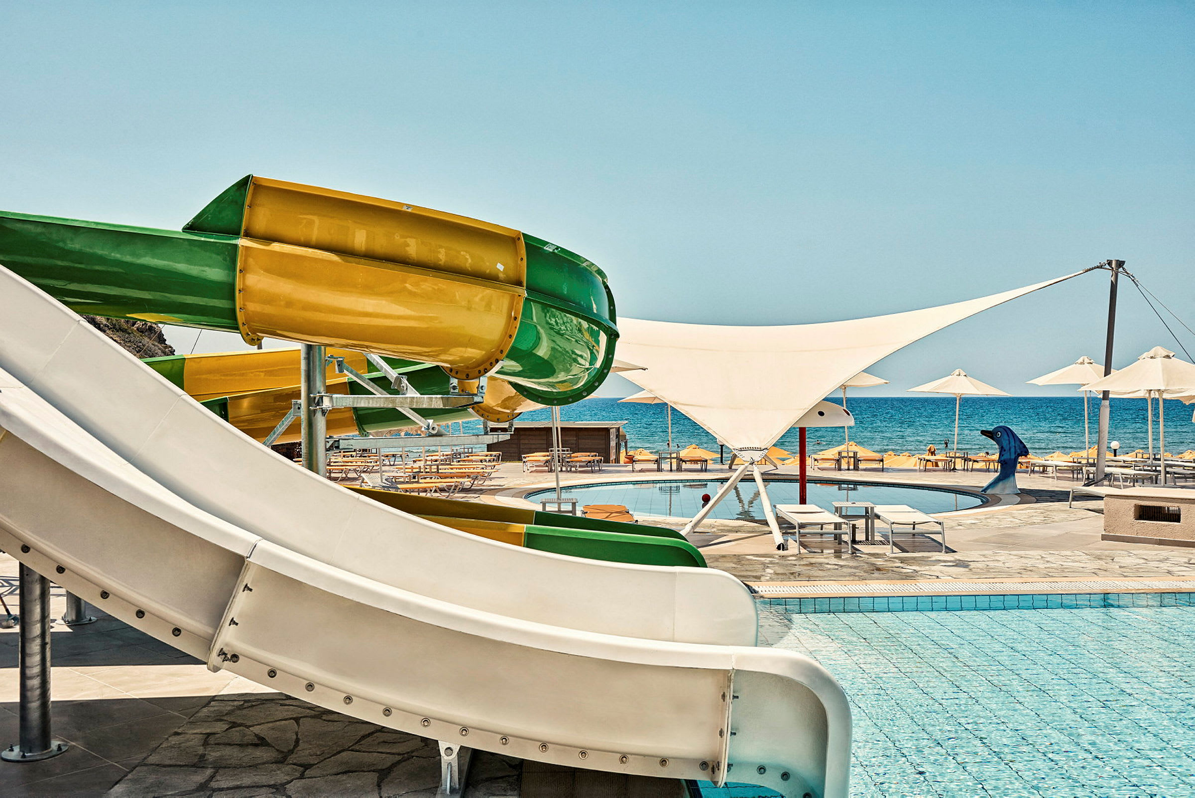 Färgglada vattenrutschbanor vid en pool nära havet. (AI-genererad text)