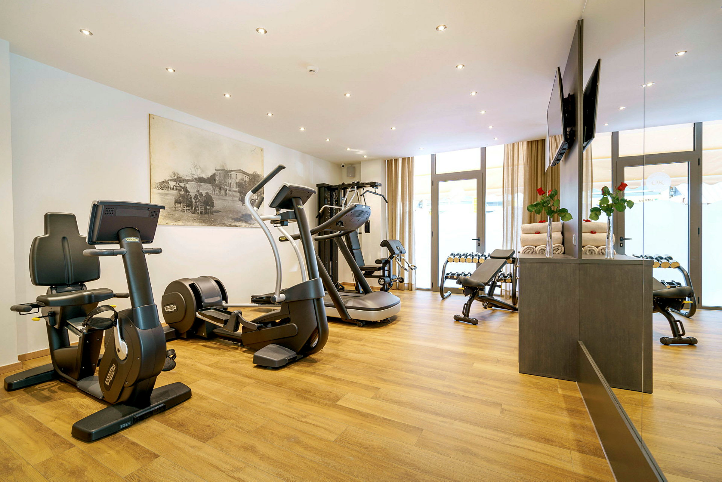 Ett modernt gym med träningsmaskiner, vikter och golv av trä. (AI-genererad text)