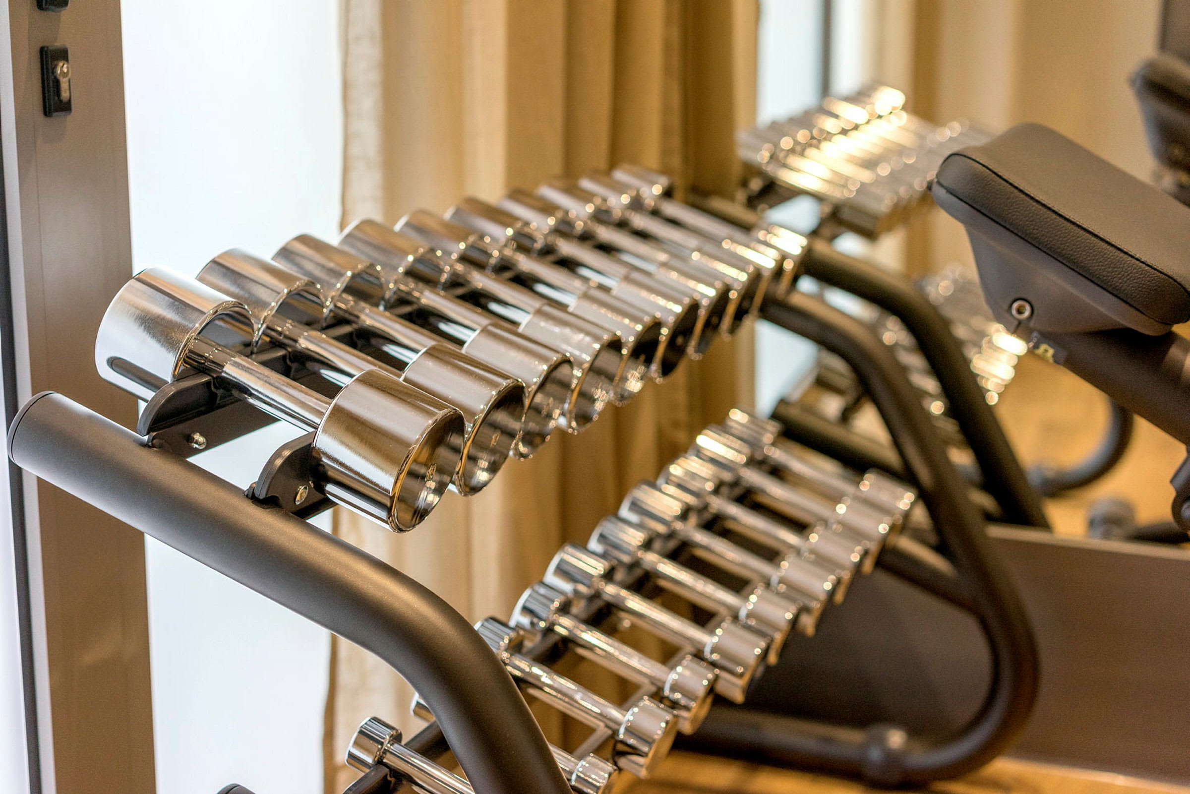 Ett ställ med silverfärgade hantlar i olika storlekar i ett gym. (AI-genererad text)