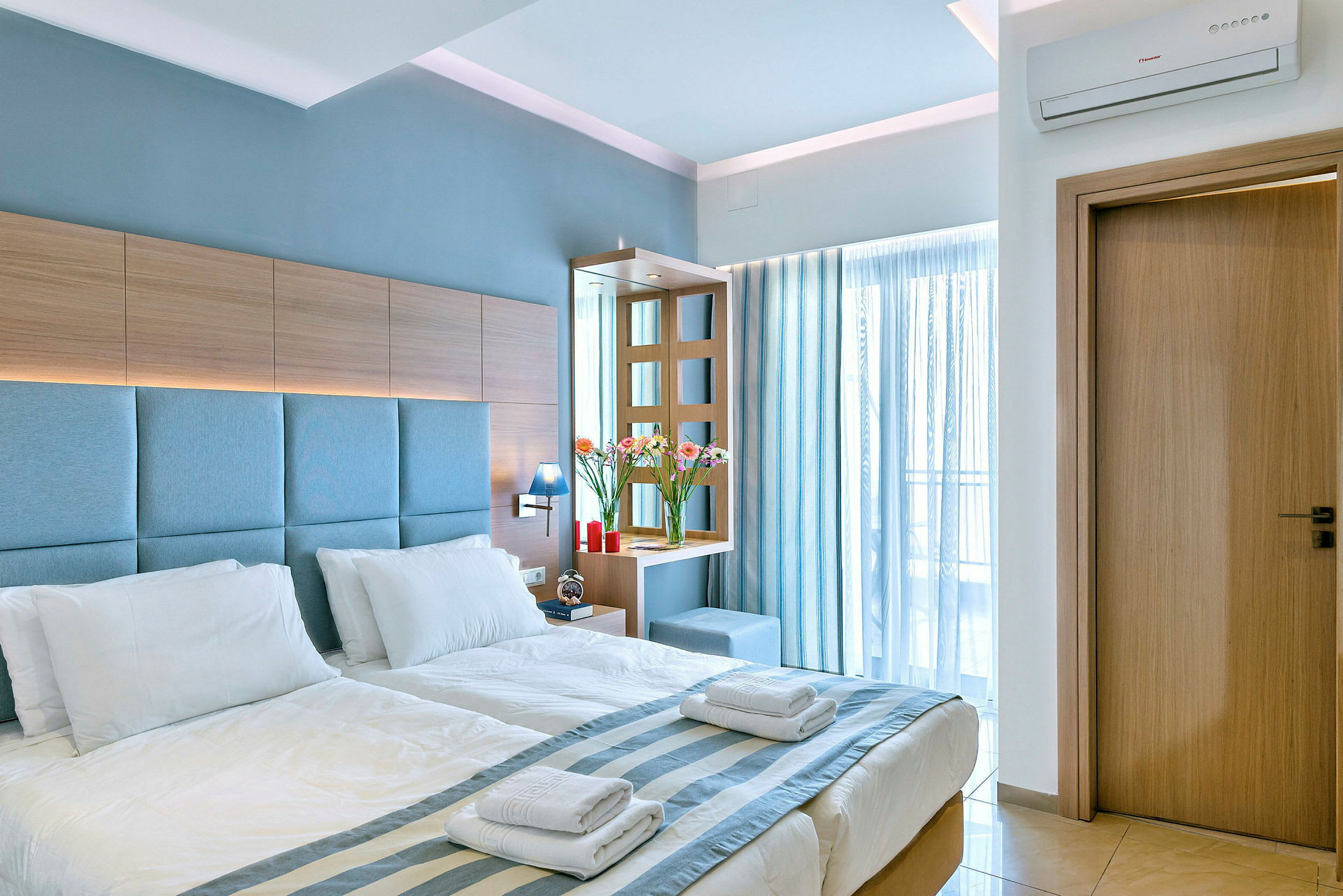 Ett hotellrum med en dubbelsäng med vita sängkläder, träpaneler och blåa detaljer. (AI-genererad text)