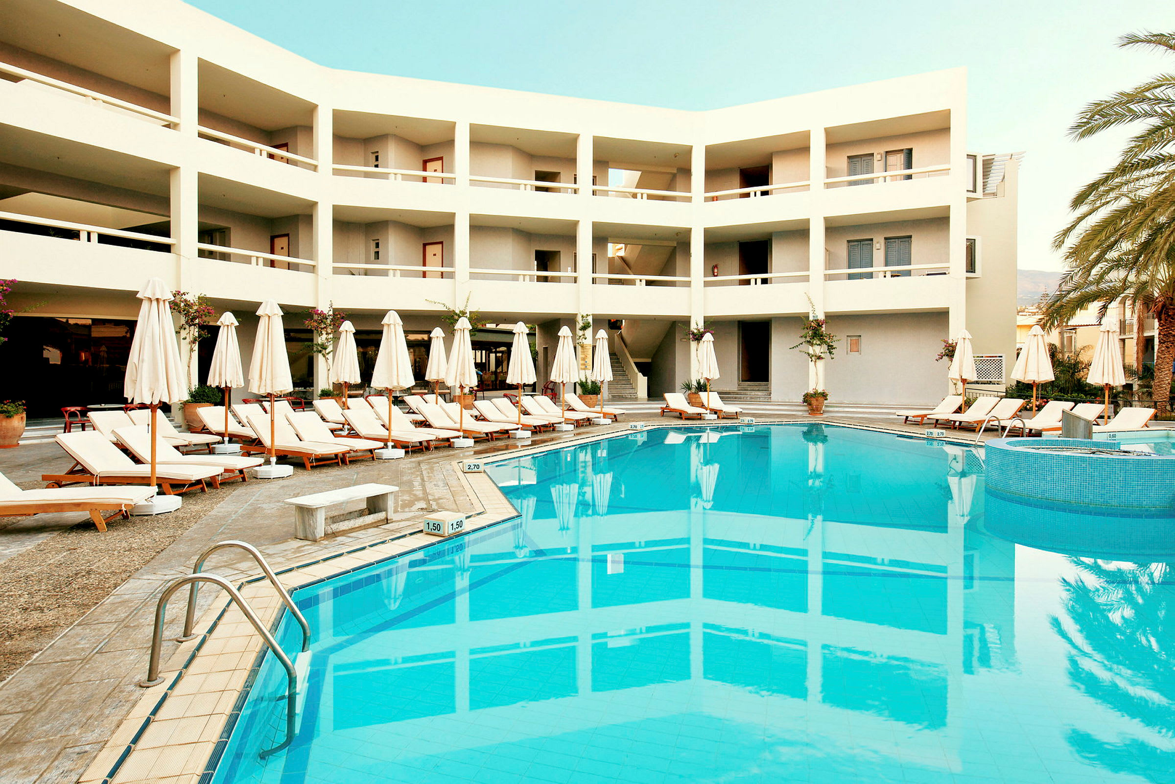 Hotellbyggnad med en pool och solstolar. (AI-genererad text)