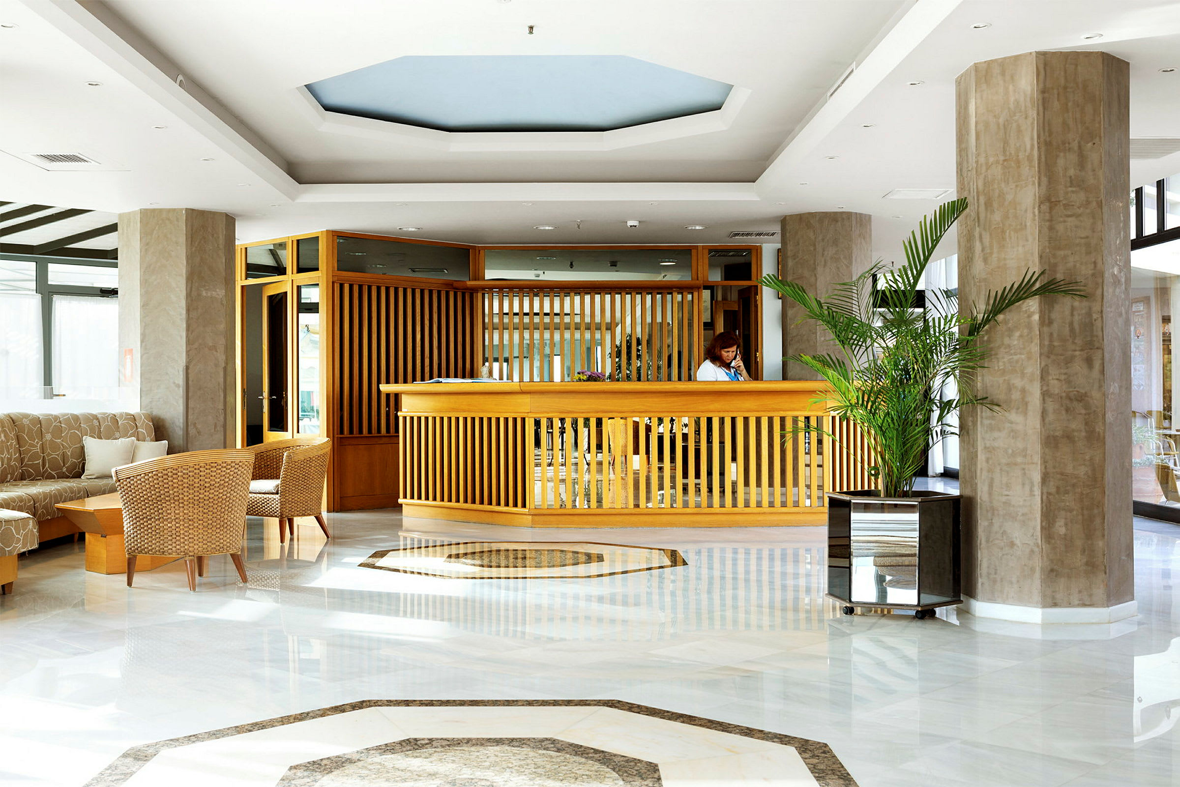 Reception i hotelllobby med träinredning och växter. (AI-genererad text)