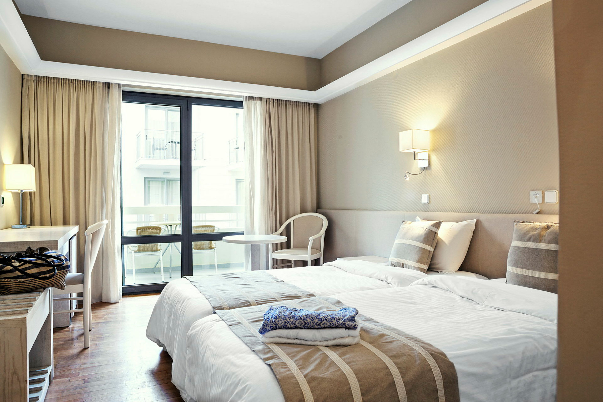 Hotellrum med två enkelsängar, skrivbord och balkong. (AI-genererad text)