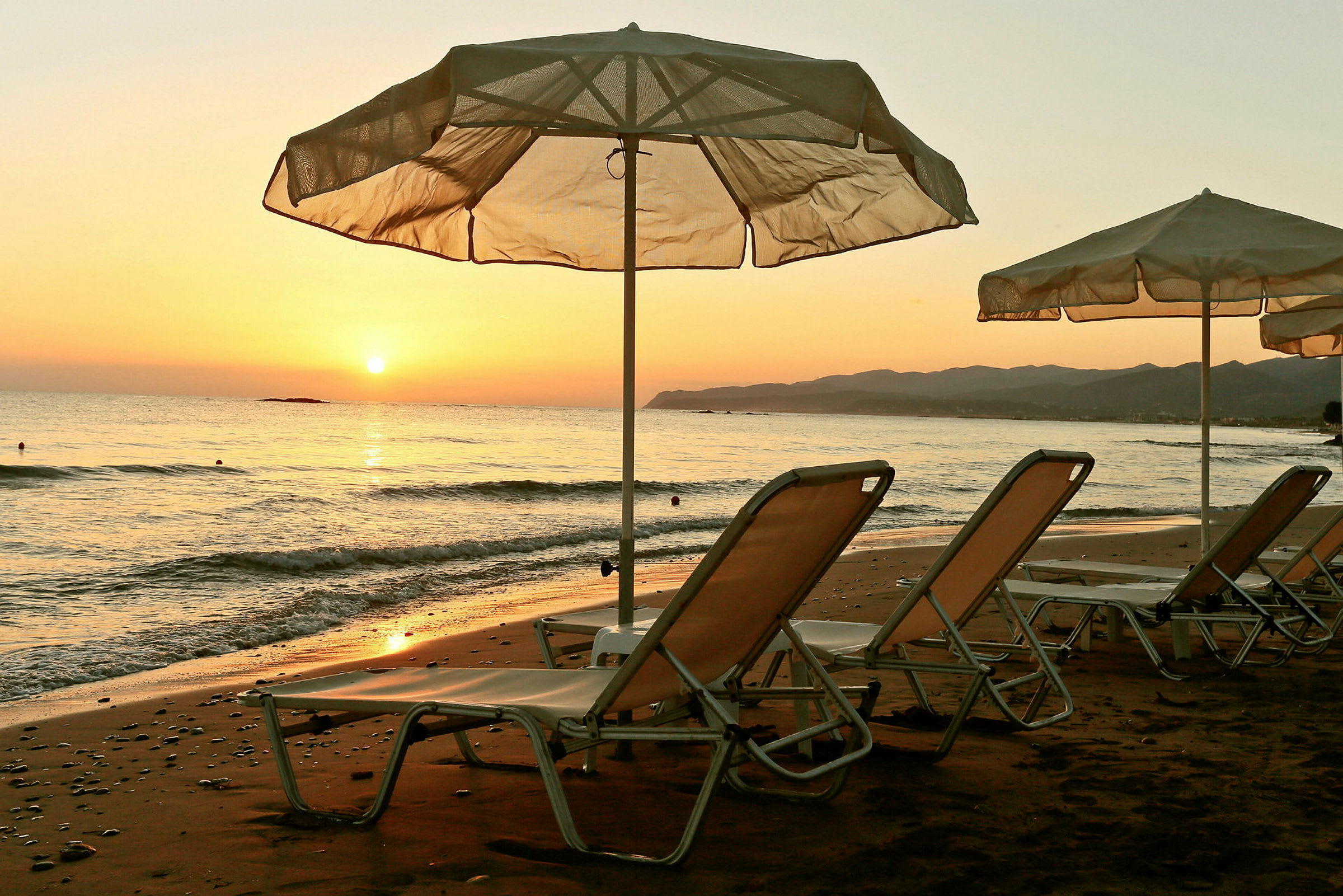 Strand med solstolar och parasoll vid solnedgång. (AI-genererad text)