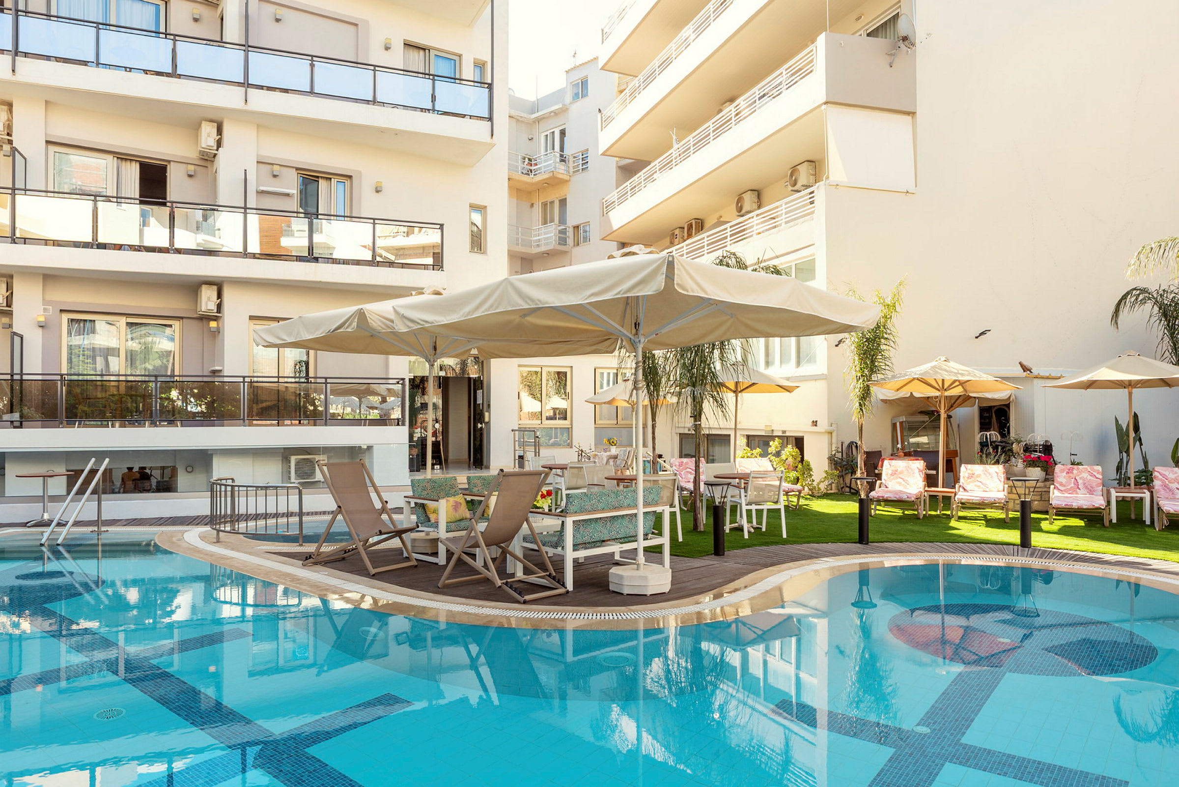 Bild av en byggnad med balkonger, en pool och en terrass med solstolar och parasoller. (AI-genererad text)
