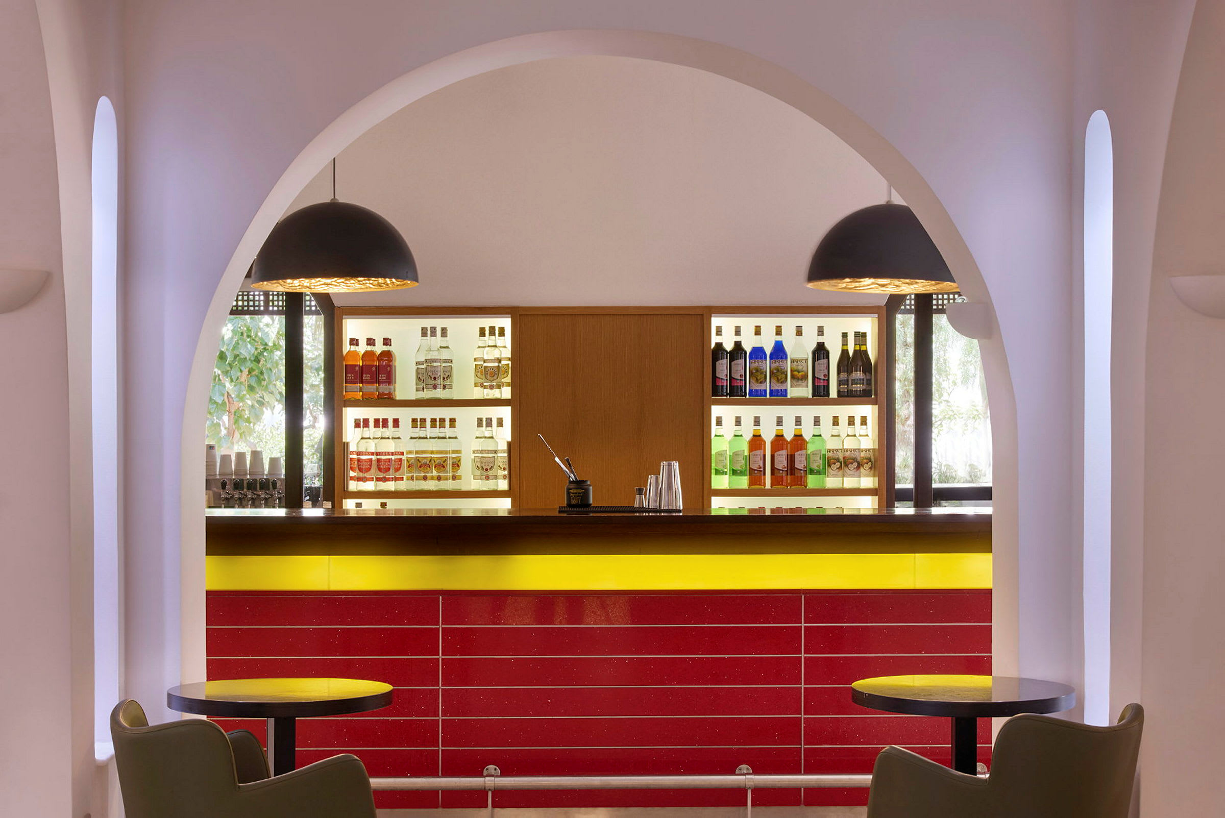 Bild på en bar med flaskor uppställda på hyllor, sittplatser och välvd arkitektur. (AI-genererad text)