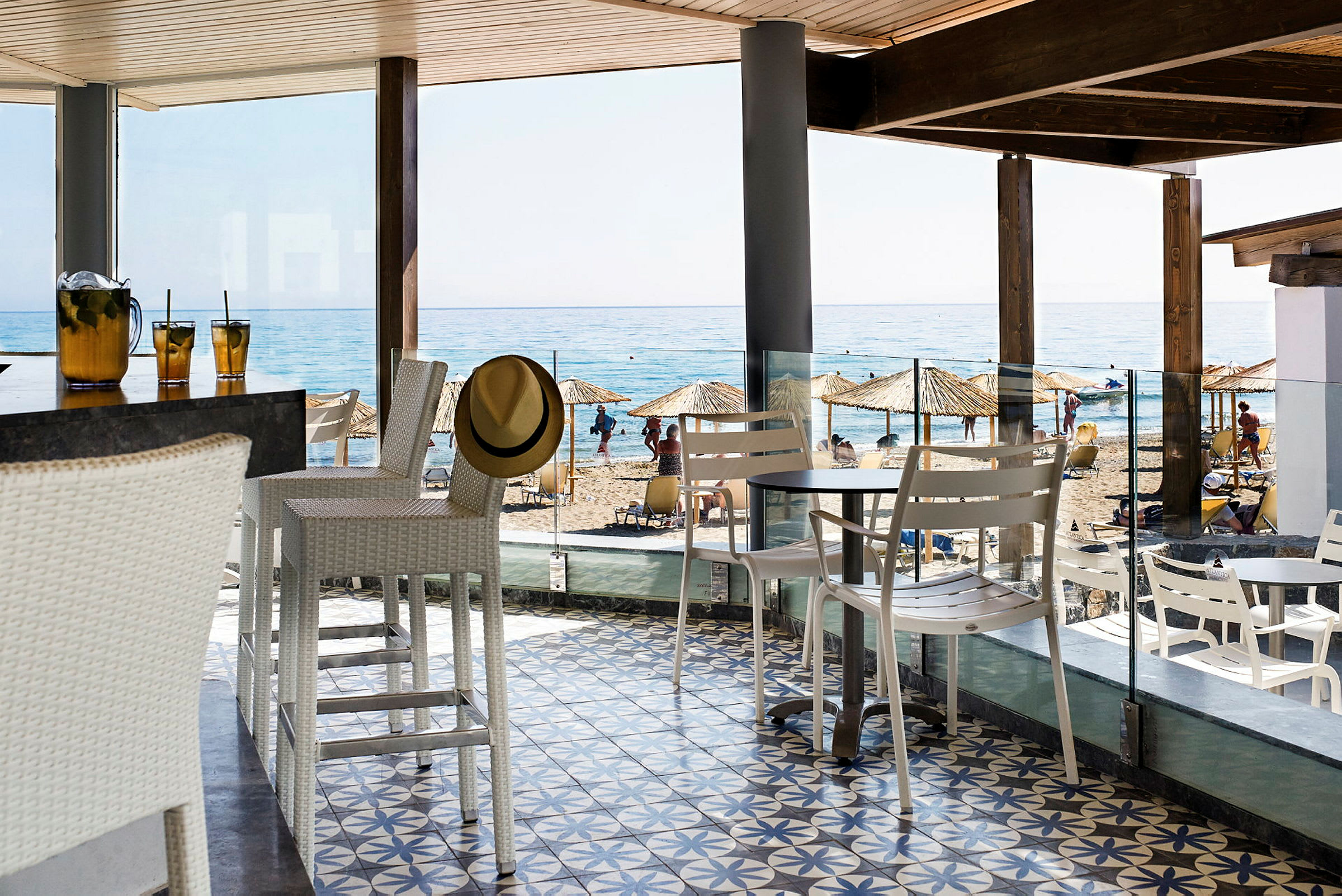 En strandbar med vit inredning. I bakgrunden syns en sandstrand och havet. (AI-genererad text)